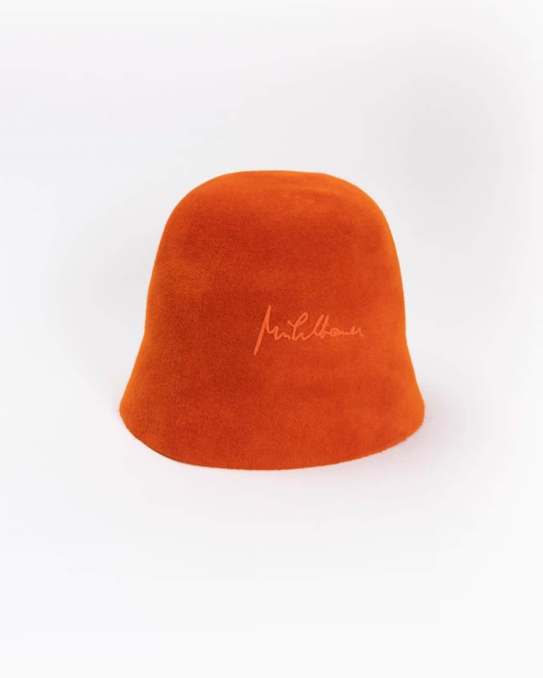 ミュールバウアーのインスタグラム：「AW 2023/24 collection CLOTH Nothing but felt! With the cloche NAJA GRIT in bright orange you will definitely not be overlooked. The highlight of our Pure Felt collection is made out of smooth velvet felt, a 100% rabbit hair felt. Its typical velvety character is achieved by the regular cut of the felt hairs. The embroided Mühlbauer signature on the side of the hat completes the design.」