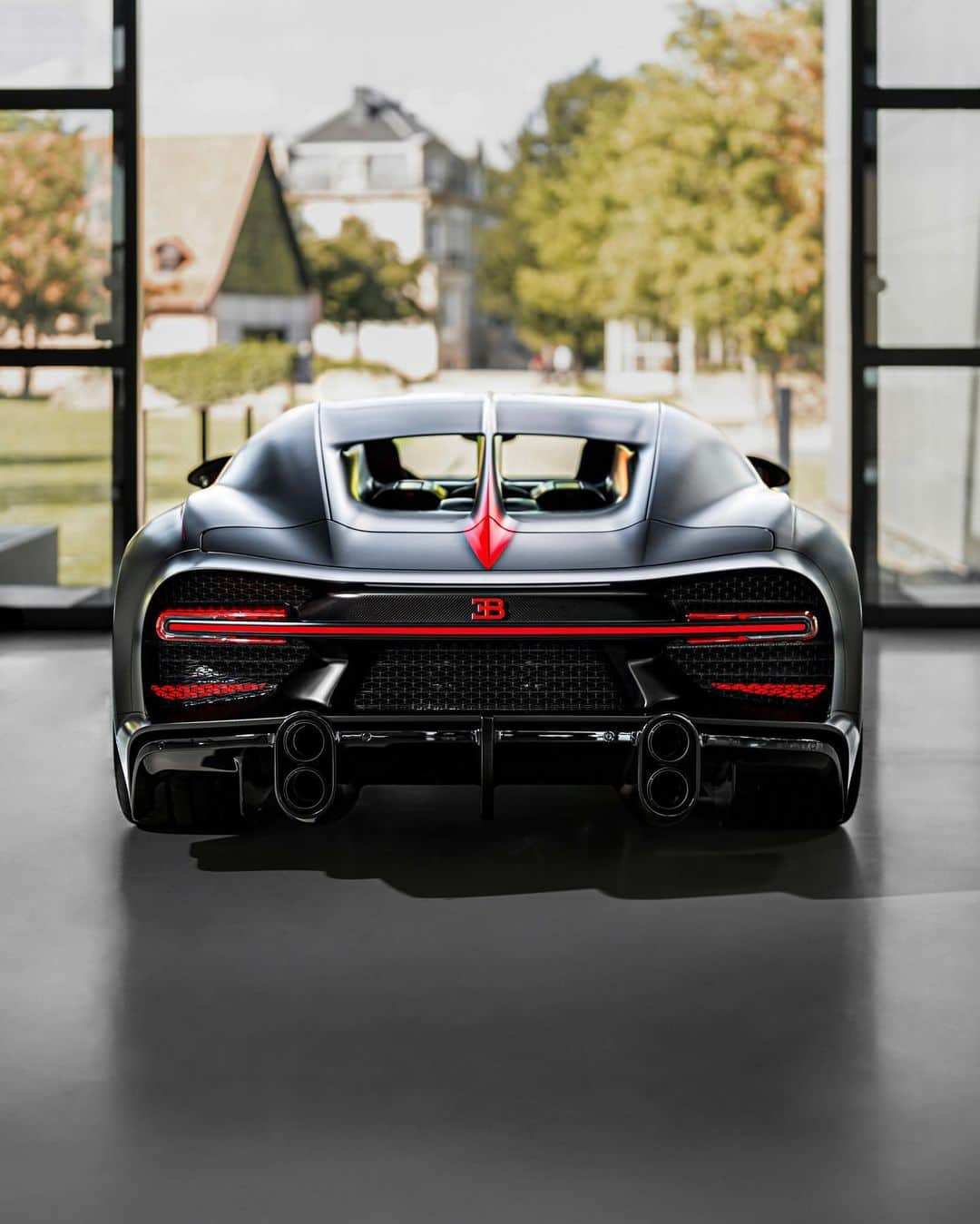 ブガッティのインスタグラム：「A creative concept envisioned by a customer exquisitely brought to life. The dream of a @BUGATTI.UAE client, the personalized CHIRON Super Sport immerses itself in Matt Beluga Black across the exterior, its finish creating an alluring tone that reinforces the uncompromising character of the performance-defining 1,600 PS hyper sports car.   Intersecting across the Matt Beluga Black is the use of Matt Italian Red – running precisely down the middle to form the vibrant center line, in the process accentuating a design inspired by perfect symmetry.   The owner’s vision for the interior was just as creative: on the driver’s side is an aesthetic immersed in the rich Italian Red; a contrasting Beluga Black engulfs the passenger side. The black anodized center console inlay is finished with the Louis Chiron signature, both doors are covered by delicate woven leather.  #BUGATTI #CHIRONSuperSport #BUGATTIUAE – WLTP: bugatti.link/consumption」