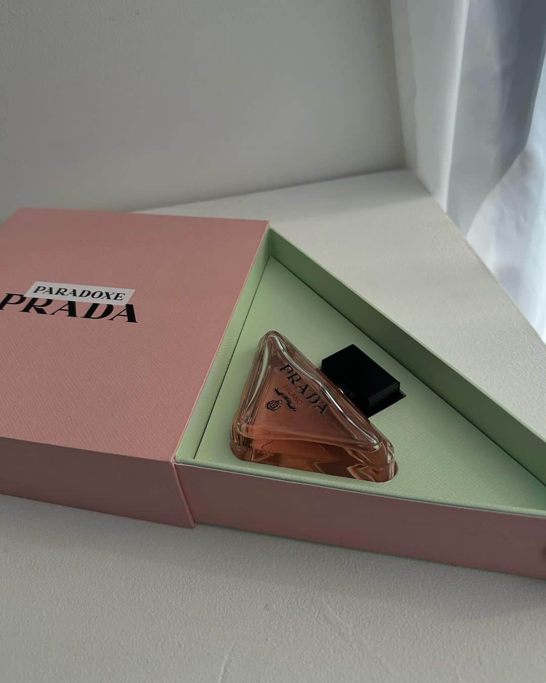 松本恵奈のインスタグラム：「おはようございます♡ pradaから素敵なギフトが届きました🎁 アイコニックな三角が可愛い♡  香りのコンセプトも素敵でした。 プラダがDNAの一つとして受け継ぐ「パラドックス（矛盾）」を反映した香り。 相反する面を持ち、様々な顔を見せながらも、 常に自分を持ち続ける、そんな「パラドックス (矛盾)」とも言える概念こそ、自分らしさの源。 ホワイトフラワーブーケを想起させるタイムレスなフローラルノートでありながらも、 対極にある強さやアバンギャルドさを表す アンバーの香りを融合。 鮮やかな明るさとともに、深みのある香りです○  素敵なギフトをありがとうございます。 朝から幸せな気持ちになりました♡ 今日から早速、使ってみよ♡ #prada #pradabeauty #フレグランス #pradoxe」