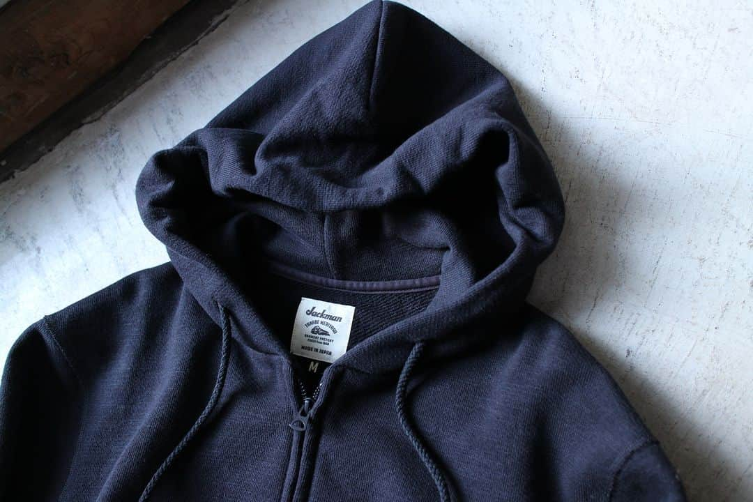 Jackmanさんのインスタグラム写真 - (JackmanInstagram)「▽ FW23 GG SWEAT PARKA JM7293 100%COTTON ￥19,800 Color:07Black   何度も改良を重ねて完成した 着やすくきれいなフォルムの スウェットジップパーカ  素材は太い番手の国産糸を使用し 日本国内で編み立てた GG(ガラガラ)裏毛を使用  昨シーズン 身巾、肩巾、着丈の設計を見直して 着心地をアップデートしました  また肩周りにゆとりを出すために 肩線にカーブをつけて立体裁断 フードが後ろに倒れないように 首周りの改良を加えました  主要部分の縫製を 縫い代がごろつかない フラットシーマーに変更したことで 肌あたりも向上  黒いボディに 黒いフードの調節用コード 黒いファスナー  そしてファスナーの金属感を隠す 務歯隠し仕様  黒くて上品な スウェットパーカです」11月23日 10時00分 - jackman_official