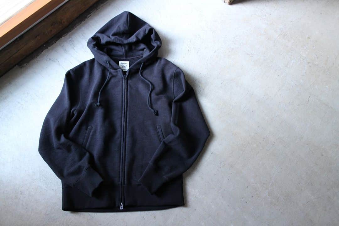 Jackmanのインスタグラム：「▽ FW23 GG SWEAT PARKA JM7293 100%COTTON ￥19,800 Color:07Black   何度も改良を重ねて完成した 着やすくきれいなフォルムの スウェットジップパーカ  素材は太い番手の国産糸を使用し 日本国内で編み立てた GG(ガラガラ)裏毛を使用  昨シーズン 身巾、肩巾、着丈の設計を見直して 着心地をアップデートしました  また肩周りにゆとりを出すために 肩線にカーブをつけて立体裁断 フードが後ろに倒れないように 首周りの改良を加えました  主要部分の縫製を 縫い代がごろつかない フラットシーマーに変更したことで 肌あたりも向上  黒いボディに 黒いフードの調節用コード 黒いファスナー  そしてファスナーの金属感を隠す 務歯隠し仕様  黒くて上品な スウェットパーカです」