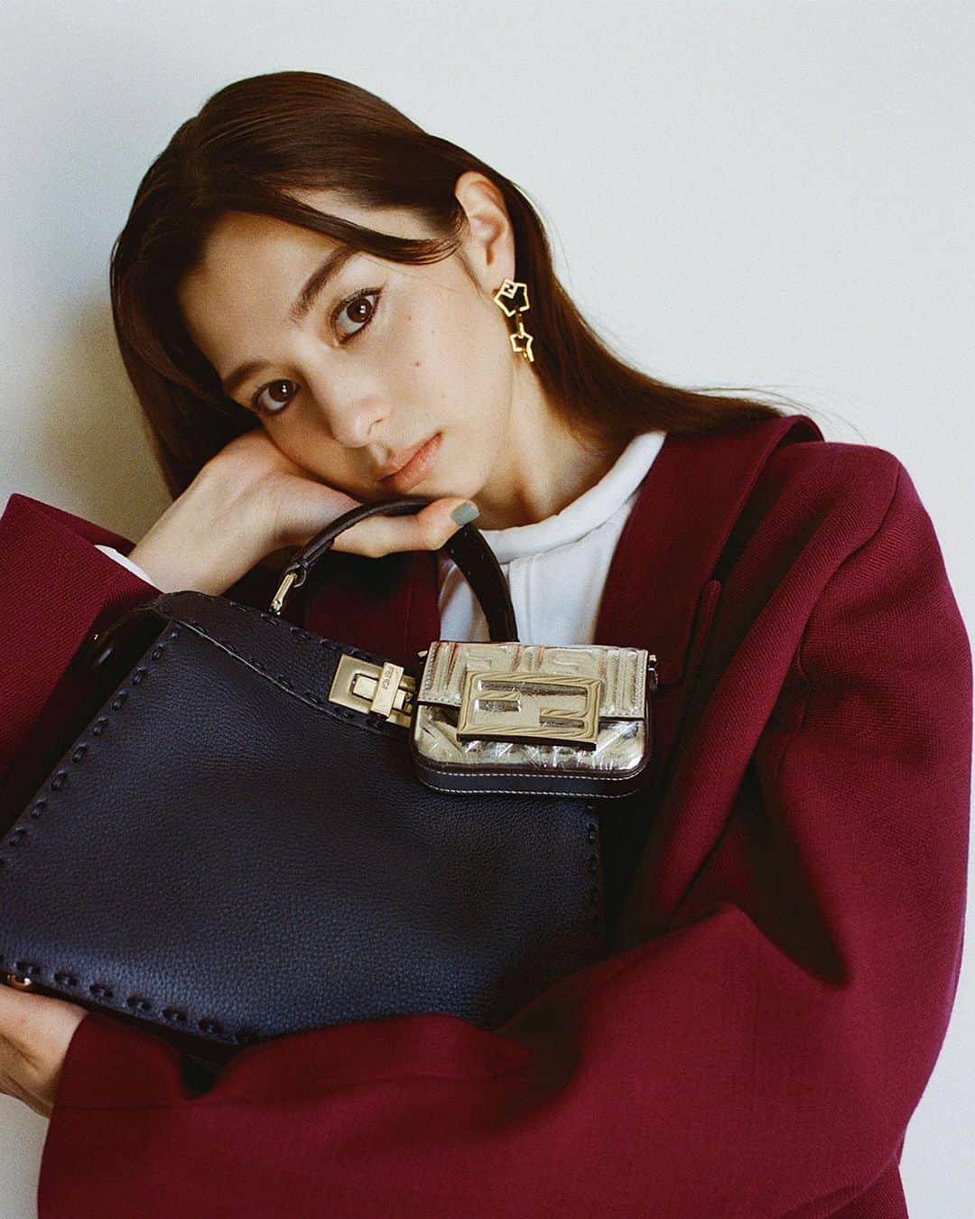 The Fashion Postのインスタグラム：「#fashion FENDI with Ayami Nakajo  『伝統を覆し、新たな個性を引き出す。中条あやみが着こなすフェンディ vol.3』  FENDI の中で「バケット」と並ぶ人気を誇るのが2009年に発売した「ピーカブー」。バッグの開閉の動作、開けると外側とは違う表情（素材）を見せることから、日本語で「いないいないばぁ」という意味をもつ「ピーカブー」という名前が付けられた。フロントの留め具を閉めるとシックな見た目だが、開けて中身のカラーやデザインを見せることで異なる印象に変化。クラシカルでありながらモダンな「ピーカブー」は、まさに二面性が表現されたバッグともいえる。  やわらかいシボが効いたレザーに太めのステッチをほどこすことで、親しみやすさをもたらしてくれる。取り外し可能なショルダーストラップ付きでハンドバッグとしてもクロスボディバッグとしても使えるのもポイント。また、アクセントとして「ナノ バゲット」をプラス。アクセサリー感覚で使えるのは、「FF」ロゴのバックルとレザーをすべてシルバーで揃えたからこそ。これらのバッグの掛け合わせが、華やかなソフトなレッドカラーのセットアップにマッチしつつも知的なイメージを連れてくる。さらに、本コレクションは男女ともに着用可というのも Stefano のこだわり。  model: Ayami Nakajo photography: Keita Goto videography: Kohei Igarashi styling: Lisa Sato hair & make up: Ryoki Shimonagata edit&text: Yuko Igarashi  #tfp #thefashionpost #FENDI #フェンディ #中条あやみ #ayaminakajo #pr」