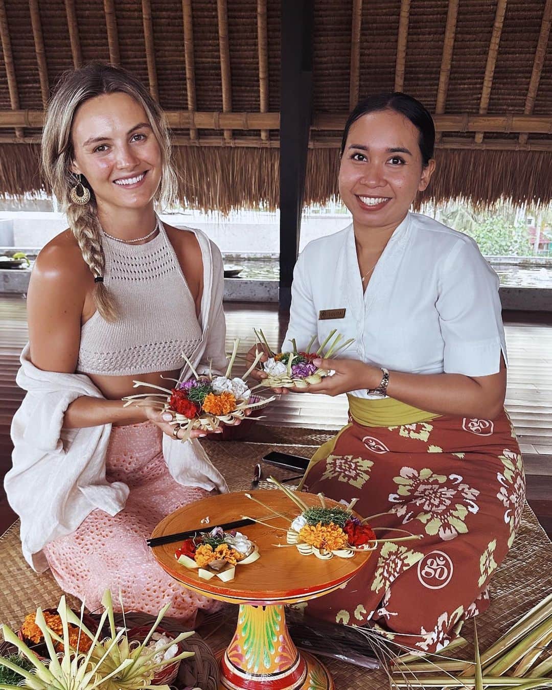 ニオミ・スマートのインスタグラム：「Terima kasih Lolita for teaching me how to make the beautiful traditional canang sari - these are the offerings that we see everywhere in Bali. They’re handmade woven baskets made from palm leaves and decorated with colourful petals and incense to pass on as an offering to the land and the gods.   What a creative way of praying & spreading love, expressing gratitude, and creating beauty on a daily basis. Within one household approximately 50 canang sari are offered in one day! I can’t think of an equivalent daily practice of offering back to the land that we do back home.   I’ve taken inspiration from this symbol of gratitude, and everywhere I’ve been during the past year I’ve created a small altar in the home with items of personal significance to me. This keeps me grounded in new environments. I’ve started offering natural items I find such as flowers or shells to the altar, creating more purpose and a connection to nature 🙏🌟🌿.   For me, this is a moment during my day to pause and consider what I’m thankful for in my life, for the guidance, the protection, and the support I feel around me. It is unrealistic to make and offer 50 canang sari a day especially when back home in the West, but taking inspiration from this and finding a personal unique daily ritual to take a moment to express gratitude I think is a beautiful thing.  If you’re considering building your own gratitude altar at home, I recommend gathering some of your most precious personal items such as sentimental ornaments, crystals, jewellery, and decorating a small table. Make it fun and get creative! I found this handwoven throw in Sumba (see last image) that I’ve used to cover the table, and decorated with petals and shells found in Bali. I’ve placed my incense, sage, and palo santo here for cleansing, and added my favourite oracle cards and crystals. I also occasionally add photos and other items that are special to me - it’s constantly evolving and growing!  If you feel called to create your own, have fun with it and know there is no right or wrong. It’s your own unique creation and practice.   🙏🌟」