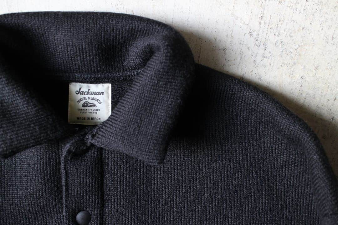 Jackmanのインスタグラム：「▽ FW23 WOOL HIMO POLO JM7382 77%WOOL 23%POLYESTER ￥24,200 Color:07Black  程よく脂分を抜いた 乾燥感のある羊毛を スライバー編み機で編み上げた イタリア製のスライバーニットを使用した 紐ポロシャツです  重くなりがちなウール素材を 快適に着用するために あえて度目を詰めず ふんわりと編み上げました  デザインは 初めてのポロとヒモの組み合わせ 裾の紐を絞ることで膨らみが生まれ ボトムスとの着合わせに 変化を加えることができます  フロントを閉める時のドットボタンも ウールのふんわり感を邪魔しない プランサータイプにしました  秋と冬の ど真ん中で  This Himo Polo shirt is made with Italian sliver knit created from dried sheep’s wool with just the right amount of fat removed using a sliver knitting machine. To make the often heavy wool material comfortable to wear, we deliberately kept the knitting loose. This design is our first time combining a polo with drawstrings. Tightening the drawstring at the hem allows you to create volume, and you can add variation by pairing it with bottoms. For the snap buttons for closing the front, we chose PLANCER-type buttons so as not to disrupt the fluffy wool feel.」