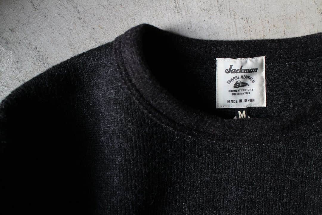 Jackmanのインスタグラム：「▽ FW23 WOOL HIMO CREW JM7381  77%WOOL 23%POLYESTER ￥19,800 Color:195 Heather Black  程よく脂分を抜いた 乾燥感のある羊毛を スライバー編み機で編み上げた イタリア製のスライバーニットを使用した 7部袖紐クルーネックシャツです  重くなりがちなウール素材を 快適に着用するために あえて度目を詰めず ふんわりと編み上げました  デザインはクラシカルな Baseballユニフォームのような袖丈と 裾の紐が特徴です  紐を少し絞ることで膨らみが生まれ ボトムスとの着合わせに 変化を加えることができます  長袖Tシャツとご一緒に 秋と冬のど真ん中で  ぜひ  インナーは JM7200 Waffle Midneck 今シーズンの新しいお色 コンクリートです  This Himo Polo shirt is made with Italian sliver knit created from dried sheep’s wool with just the right amount of fat removed using a sliver knitting machine. To make the often heavy wool material comfortable to wear, we deliberately kept the knitting loose. This design is our first time combining a polo with drawstrings. Tightening the drawstring at the hem allows you to create volume, and you can add variation by pairing it with bottoms. For the snap buttons for closing the front, we chose PLANCER-type buttons so as not to disrupt the fluffy wool feel.」