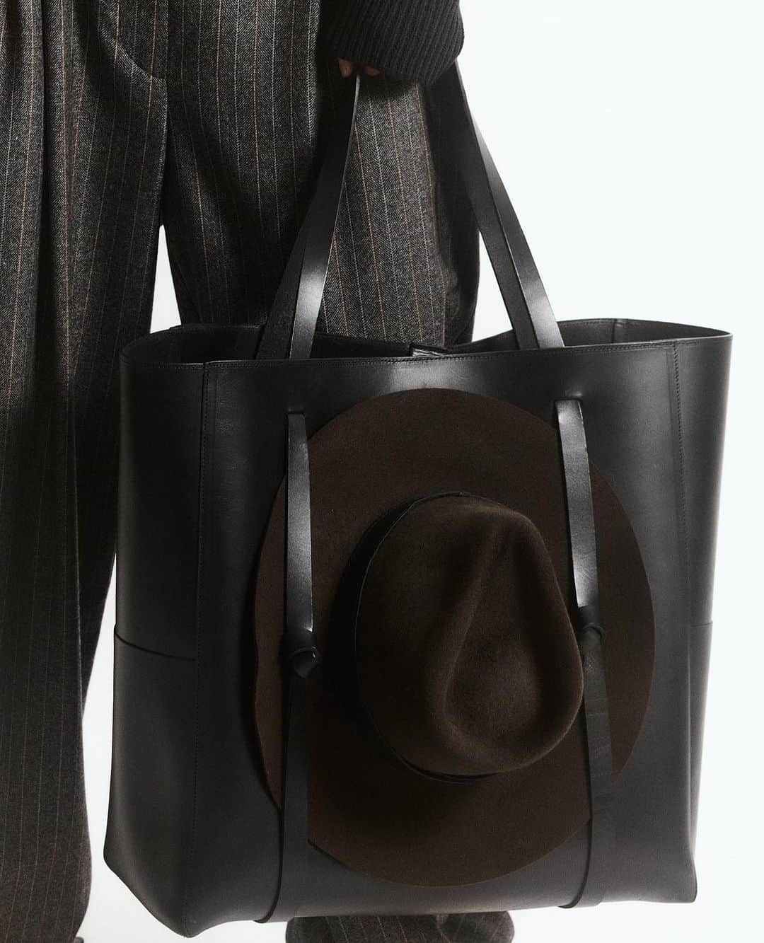 JanessaLeoneのインスタグラム：「NORA___ A large classic tote featuring a brass hook closure and a special hat holding feature designed for ease when traveling.」