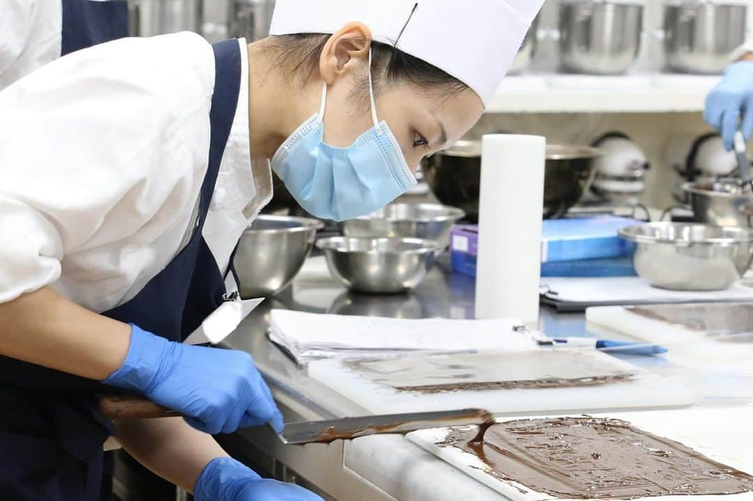 神戸製菓専門学校（公式）のインスタグラム：「🌙関西唯一、夜間1年制で製菓を学べるお菓子専科🌙  夜間部でも1年間の約90％が実習・演習❗️ 昼間は働いたり、大学とWスクールしたり 1日の時間を有効に使いながら 基礎から応用まで製菓技術を幅広く学びます😊  今日はチョコレートのテンパリングの実習🍫  前回は水冷法、今回はフレーク法を修得。 テンパリングの後はチョコレートが固まらないうちに 手早く、均一な薄さで伸ばすのが重要です😌  何度も練習する中で、綺麗なパーツが 取れるようになってきました✨👏  ★これから夜間部の進学を検討されている方へ★ 年内はあと4回、実習見学会を開催します❗️  11/24(金)満席 12/1(金)残りわずか 12/8(金)残りわずか 12/22(金)空きあり  18:30～19:30で学校終わりやお仕事帰りにも😌 ぜひ実際の雰囲気なども見て進学を検討してみてください★ 気軽にご参加、お待ちしております✨  #神戸製菓　#お菓子専科　#夜間部　#夜間　#専門学校　#製菓専門学校　#神戸製菓　#学び直し　#社会人　#大学生　#再進学　#パティシエ　#パン職人　#チョコレート　#🍫　#ショコラティエ　#神戸　#三ノ宮　#pattistagram2023」