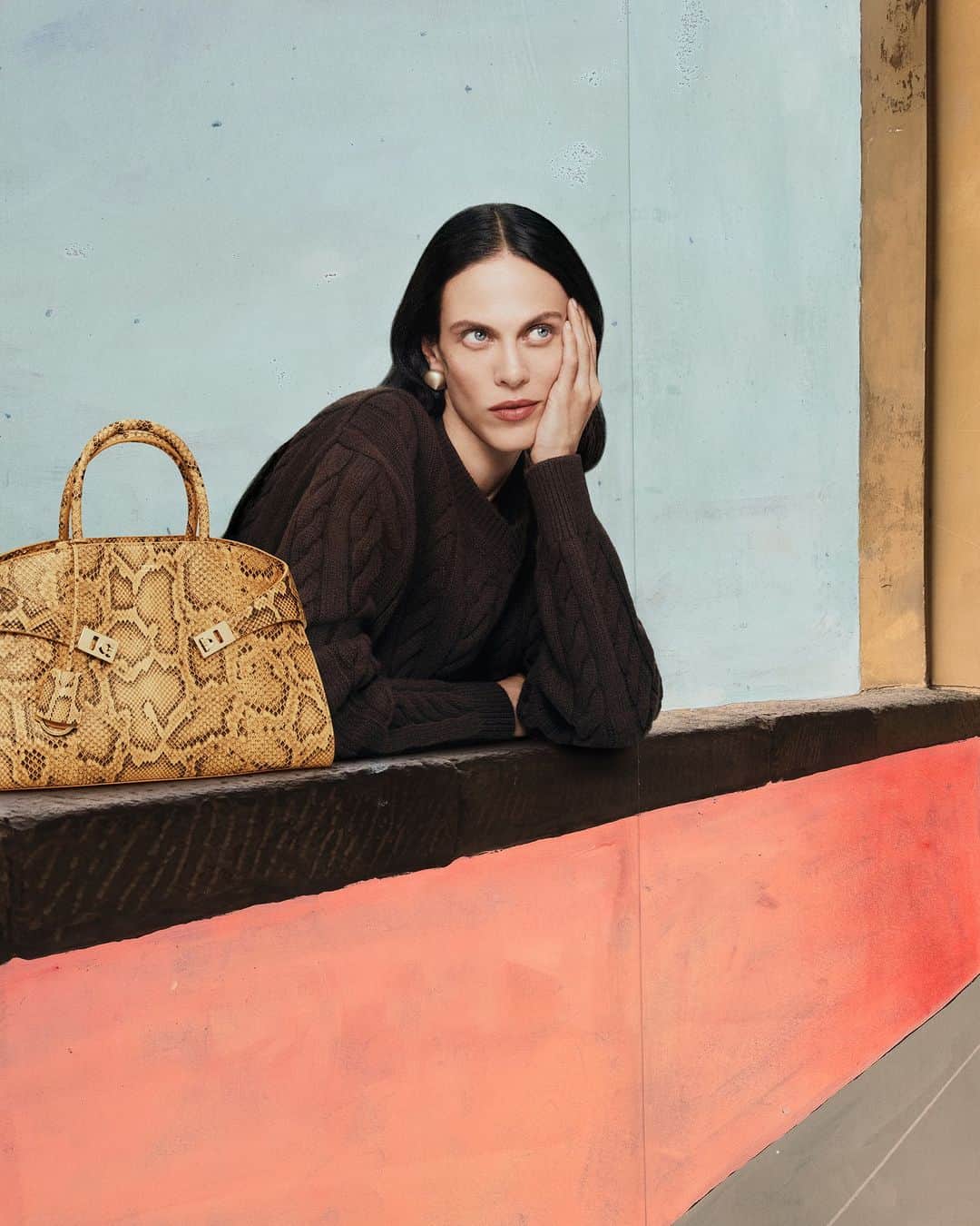 サルヴァトーレ・フェラガモのインスタグラム：「A special iteration of the Hug Bag imagined on the Vasari Corridor, an elevated enclosed passageway above the city which starts from the ground floor of the Uffizi, to reach the Medici’s Boboli Gardens and the Grand Ducal abode of Palazzo Pitti.   By permission of the Ministry of Culture – Gallerie degli Uffizi.  Campaign concept and Creative Direction @ferdinandoverderi Lensed by @rafaelpavarotti_ Paintings by @paolo.ventura」