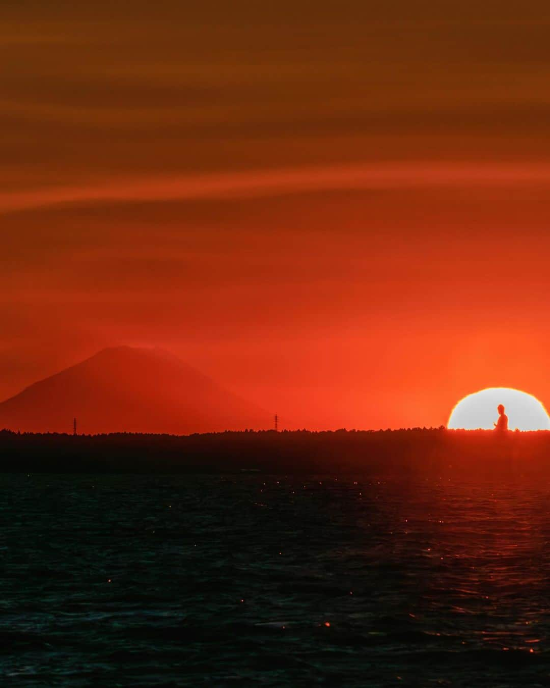 SHOCK EYEのインスタグラム：「富士山、大仏、そして太陽☀️ この３者が一つの画角に入る景色✨  ずっと見たくて、 先日ついに撮影しにいくことができました✨  大気が少しガスっていたので、くっきり富士山とはいかなかったけれど、神秘的な瞬間に出会えて、とても感動したよ。  すごかったのが、 陽が沈んだあと、富士山から空に向けて斜めの影がビーンって伸びてて、 それがとても不思議な光景だった✨🧐  この景色はまた何度かトライしてみたいなあ。 次は、ダイヤモンド富士に大仏という構図もいいかもしれないね🤤  是非また。  サポートしてくださった、 @sadashima117  ありがとうございました。  #富士山 #牛久大仏 #mtfuji #ushikudaibutsu」