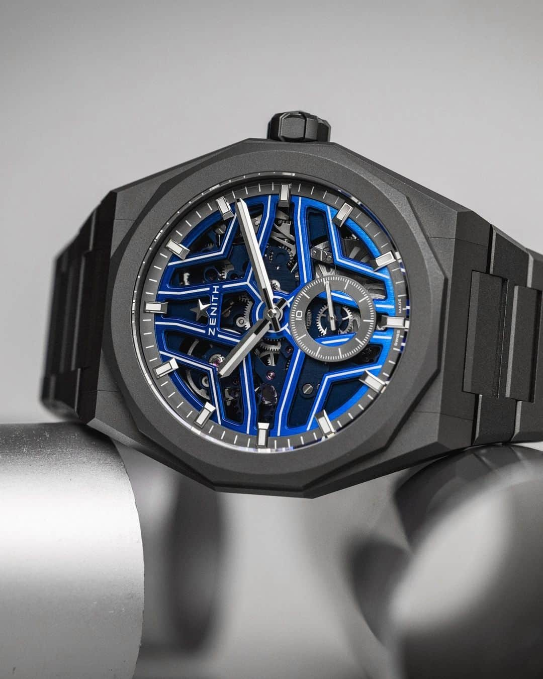 ゼニスのインスタグラム：「Now available exclusively online⭐🌊 The #DefySkylineSkeleton Night Surfer #ElPrimero in collaboration with @timetidewatches shines bright: Its bright liquid blue gradient dial is framed by a complimentary dodecagonal bezel & integrated bracelet crafted in microblasted titanium. At night, the open star-shaped dial is highlighted with luminescent lines, making the star motif brighter, all while highlighting the 1/10 of a second El Primero movement.」