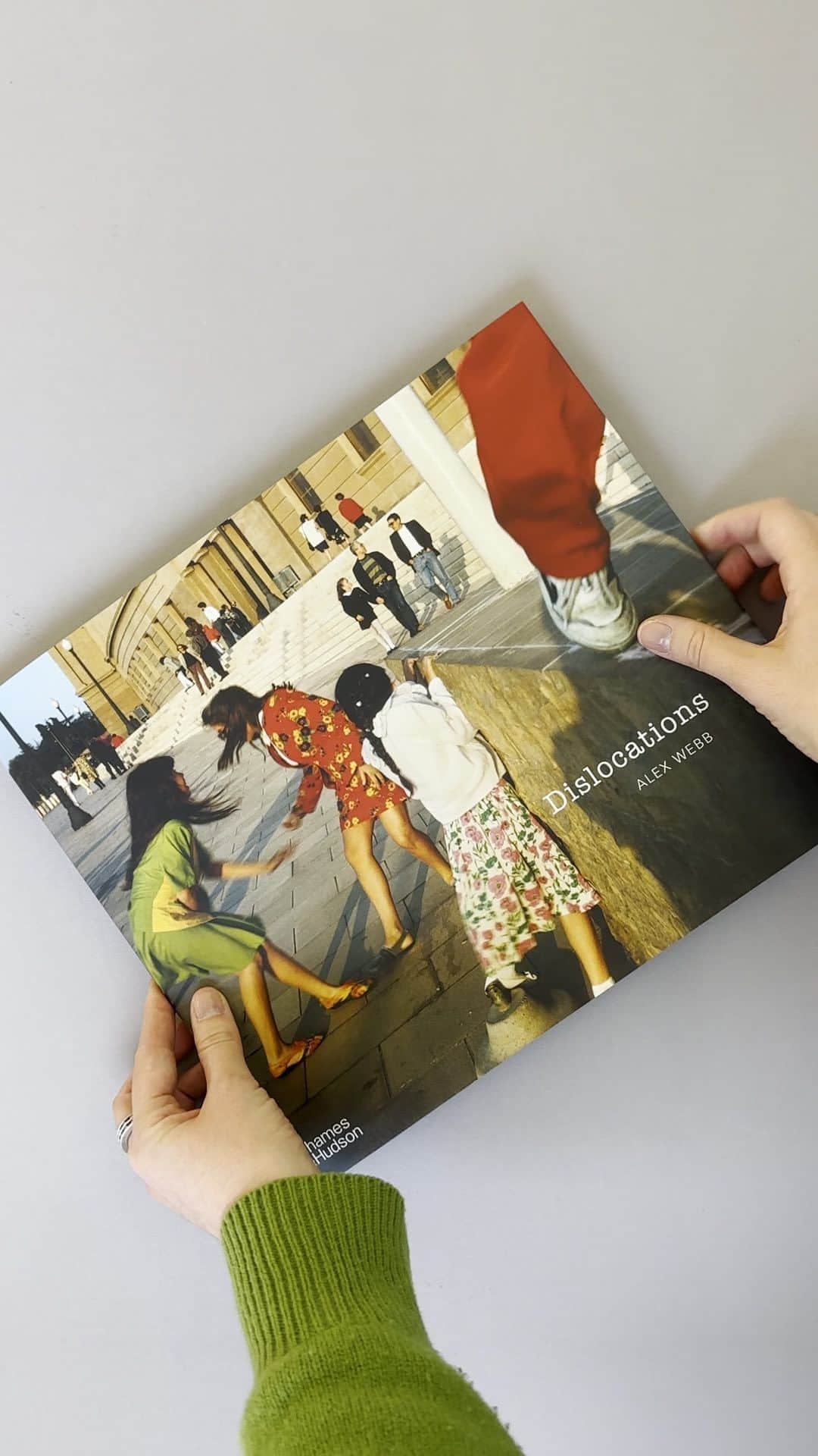 Magnum Photosのインスタグラム：「#MagnumBookClub: Dislocations by Alex Webb (@webb_norriswebb) 📖  Browsing the Magnum Photos library in London, Retail & Publications Manager @chilli.power picks up a copy of Alex Webb’s Dislocations. Published by @aperturefnd and @thamesandhudson, the new release from Webb is a reimagined and expanded edition of his long out-of-print book of the same name, originally published in 1998 as an experiment in alternative book-making.  🔗 Dislocations is currently available from our bookshop, tap the link in the @magnumphotos bio to browse our selection of books.   #AlexWebb #MagnumPhotos #photobook #Aperture」