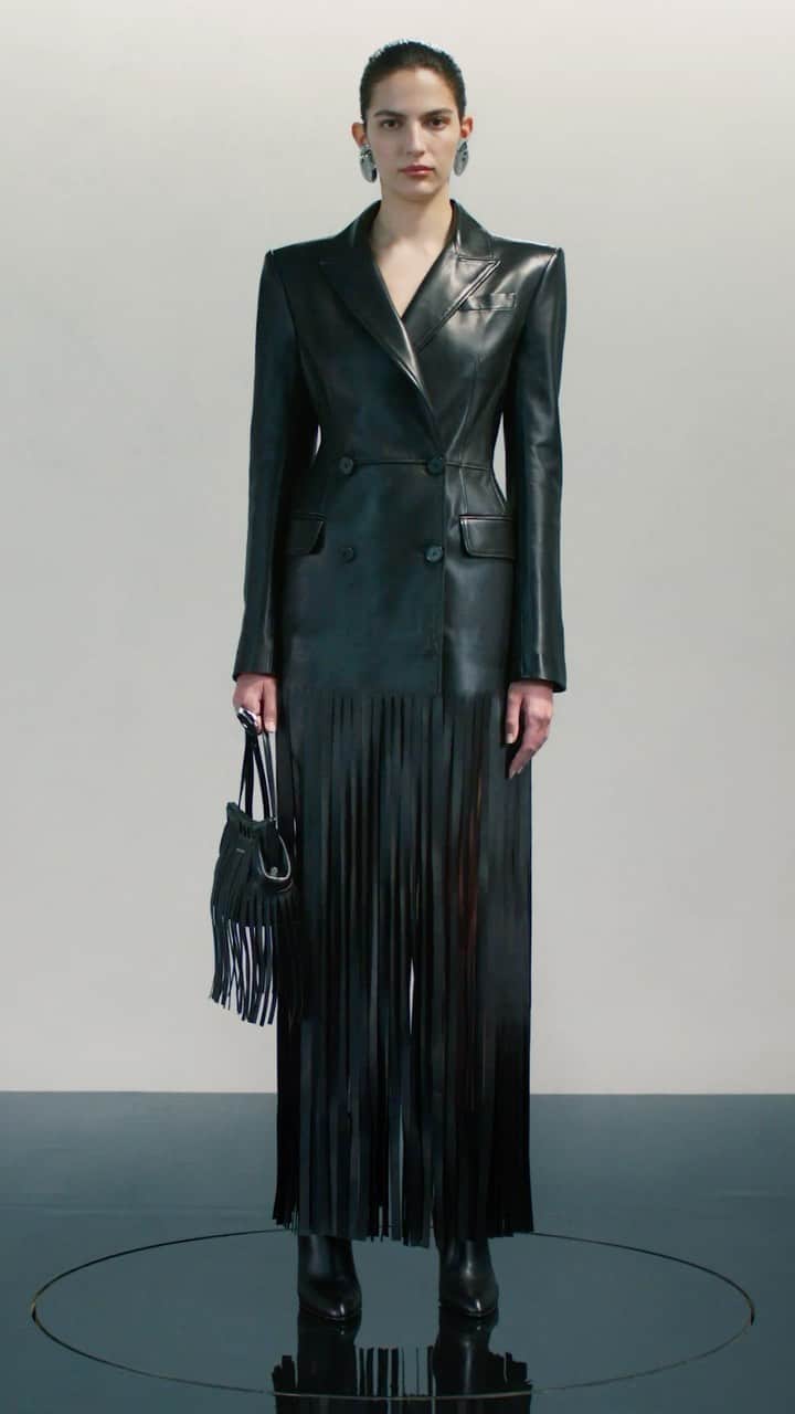 アレキサンダー・マックイーンのインスタグラム：「A black double-breasted tailored coat with a bonded fringe hem, completed with the new fringed #McQueenPeak bag in black and the #McQueenArmadillo boots.  Discover #McQueenPreSS24 via the link in bio.  Video by @EbbaHult⁣⁣ Music Director - John Gosling ⁣ Track - Umbra by Sam Bower」