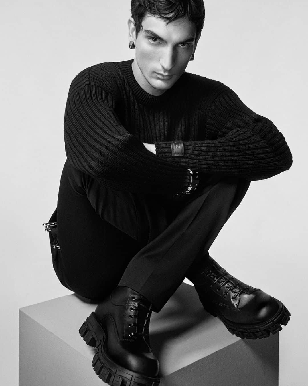 ジャンニヴェルサーチのインスタグラム：「Greca Portico Boots for #VersaceFW23  Luca wears ribbed-knit sweater; pants; Greca Portico boots  Photography by Ilya Lipkin  #Versace」