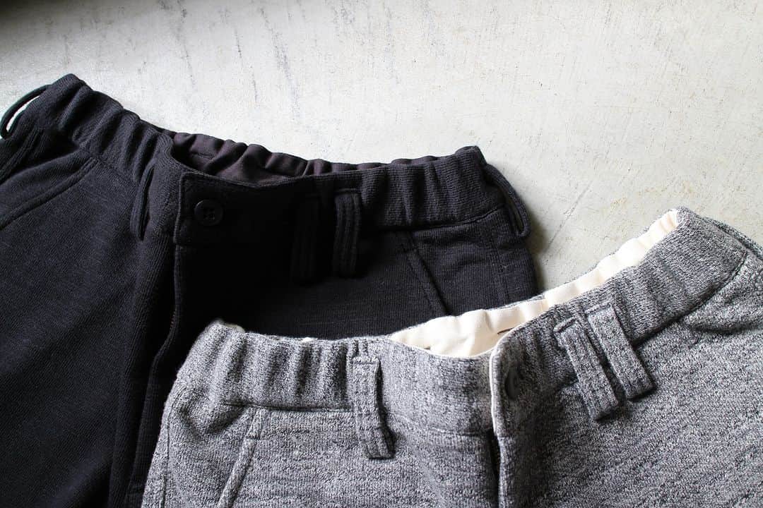 のインスタグラム：「▽ FW23 GG SWEAT TROUSERS JM4292 100%COTTON ￥18,700 Color: 07Black 29Charcoal  太番手の国産糸を使用し 日本国内で編み立てた GG(ガラガラ)裏毛素材の スウェットトラウザーです  ガラガラの名称は杢糸の濃淡差が強く 杢感が際立っていることから ネーミングしたものです  杢糸を使用したカラーは 数色の撚糸を配合し バランスの良い杢感になるように工夫 ソリッドカラーは肉厚感を重視しました  昨秋アップデートして きれいなシルエットを 維持することを優先に設計  肉厚な素材とのバランスを考え ヒップ周りと太ももわたりの 無駄な部分を削り 細身で動きやすく そして美しいシルエットに改良しました  ウエストはゴムの伸縮でアジャストできますが 幅広い着用シーンを考えて ベルトの装着も可能な設計にしました  この季節 穿いたらやめられない 綿100%トラウザー 室内でも屋外でも  The GG (Garagara) Sweat Trousers are made from French terry fabric knitted in Japan using thick, Japan-made yarn. The name “Garagara” was inspired by the sharp light/dark contrast of the heathered yarn, which gives the fabric a distinctive grainy look. The colors that use heathered yarn blend several colors of twisted yarn for a well-balanced, grainy look, while the solid colors emphasize a thicker feel. Last fall, we updated the design with priority given to maintaining a clean silhouette. To better balance the thick material, we removed excess ease around the hips and thighs for a slimmer, more flattering silhouette with greater mobility. The trousers have an adjustable elastic waistband, but the design also allows for the use of a belt to accommodate a wide range of wearing styles.」