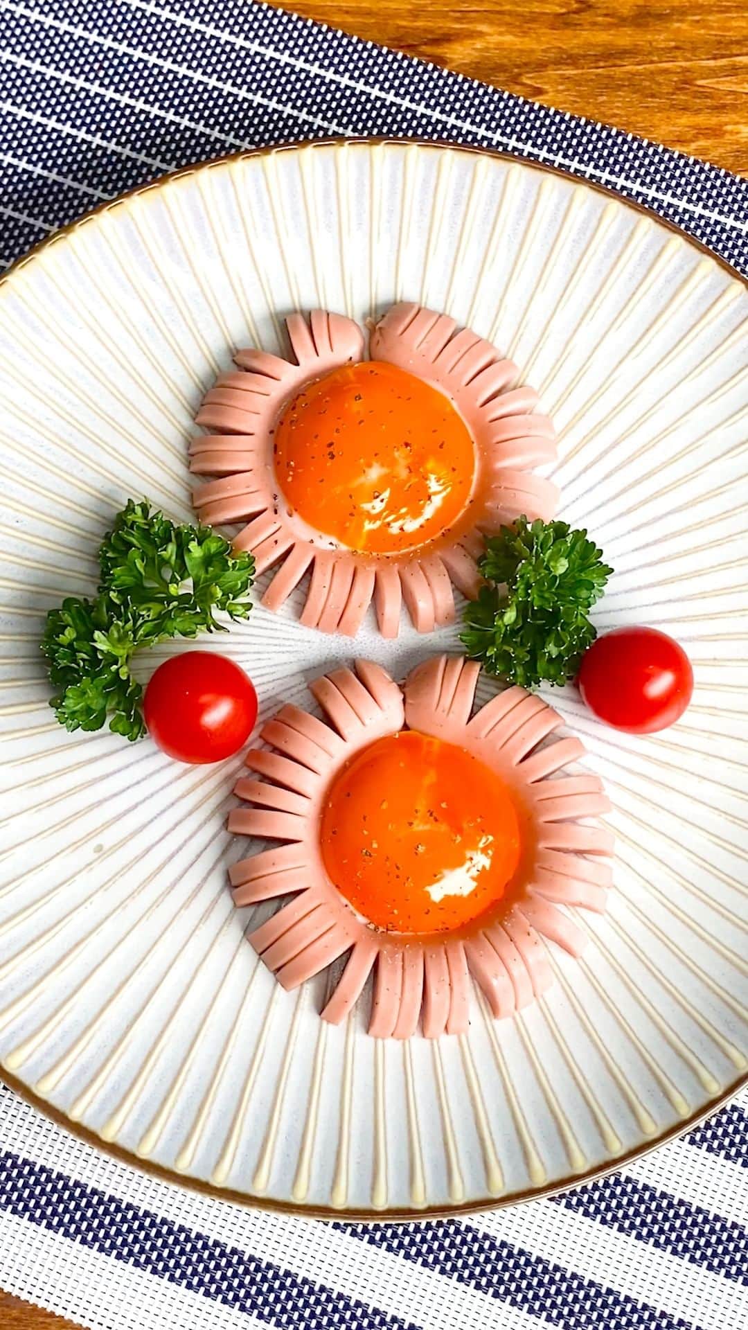 Tasty Japanのインスタグラム：「@tastyjapan 👈他のレシピもチェック！ 【発想勝ち！】明日の朝は卵とソーセージでこれ作ってみて！  レシピが知りたい方はプロフィールのリンクをクリックしてね♪  ===  Flower Sausage Servings: 1  INGREDIENTS 1 fish sausage 2 egg yolks Black pepper, as needed  PREPARATION 1. Sandwich the sausage with chopsticks. Make cuts. 2. Cut the sausage vertically. Boil in the hot water for 1 minute. 3. Bend the sausage in a circle and close with a toothpick. 4. Put some vegetable oil in a pan. Place (3) on a pan and put the egg yolk in the center. 5. Cook on medium heat for 3 minutes. Sprinkle with some black pepper. 6. Enjoy!  #tastyjapan #ソーセージ #フラワーソーセージ #目玉焼きアレンジ」