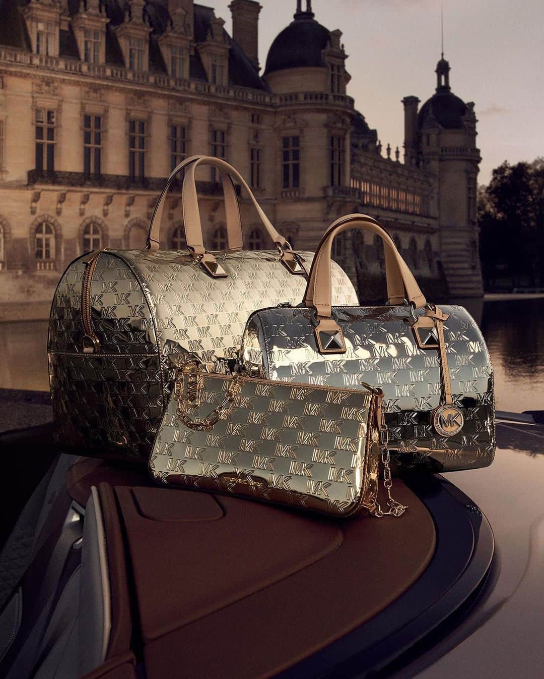 マイケルコースのインスタグラム：「Mirror, mirror. Metallic twists on our logo-embossed handbags and luggage deliver major impact.   Captured at Chateau de Chantilly in France. #MichaelKors   Photographed by @MaximePoiblanc」