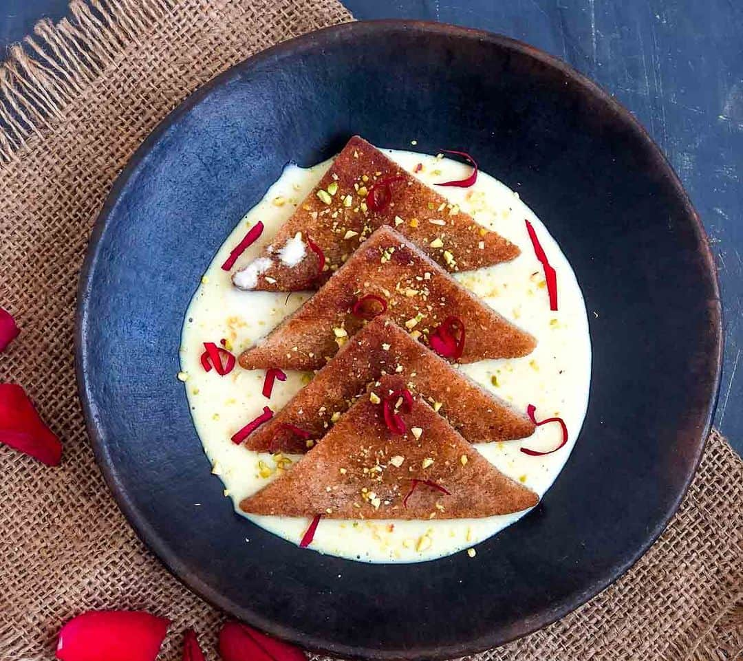 Archana's Kitchenさんのインスタグラム写真 - (Archana's KitchenInstagram)「#DiwaliRecipes   The Rose Flavoured Shahi Tukda Recipe is a delightful twist on the classic dessert, and it is sure to impress your guests. Whether you are hosting a dinner party or looking for a sweet treat to enjoy at home, this dessert is a must-try. So why not give it a try and indulge in the royal flavors of India?  For the Shahi Tukda 4 Whole Wheat Brown Bread Ghee, for shallow frying 2 tablespoons Sugar 1 tablespoon Water 1 teaspoon Rose water For the Rabri/ Basundi 2 liter Milk 3/4 cup Sugar 1 pinch Cardamom Powder (Elaichi) Rose Essence , few drops Rose Petals , to garnish Pistachios , finely chopped, for garnish  👉We will first have to condense the milk. To do this, place the milk on high heat over a heavy bottomed saucepan and bring it to boil. 👉Add the sugar and stir continuously until the sugar dissolves. Once the sugar has dissolved and the milk is boiling vigorously for a few minutes reduce the heat to low and simmer the milk mixture stirring continuously until it is reduced to three fourths of its original quantity. 👉The condensation will cause the cream from the milk to settle on the sides and bottom of the pan. It's important to keep scraping down the cream and adding it back to the condensing milk. 👉The mixture will begin to thicken and get a creamy texture. It is important to make sure towards the end of the condensing process to be close to the stove monitoring the milk and stirring it continuously. 👉The last stage is when the condensed milk can get burned at the bottom of the pan and completely alter the taste of the basundi. 👉Once the milk has reduced to half of its original quantity, turn off the heat. Add the rose essence and mix. 👉Transfer the Basundi (Rabri) to a serving dish and allow it to cool before you can refrigerate for 3-4 hours.  👉Cut each bread slice into 4 triangles.  👉Heat a saucepan on medium flame, add ghee, and place the bread triangles. Shallow fry on both sides till you get a deep golden colour. Remove from the pan and set aside. 👉In another pan, combine sugar, water and rose water and bring to a single boil. Turn off the flame. Dip the fried bread slices in the sugar syrup, drain and set aside.」10月31日 14時30分 - archanaskitchen