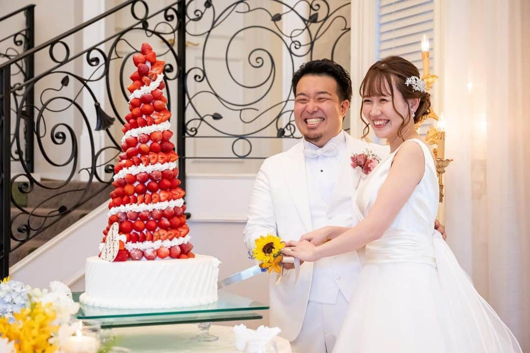 アートグレイスウエディングコースト大阪のインスタグラム：「ケーキセレモニー🍓  こちらのケーキはアートグレイスウエディングコースト 大人気のウエディングケーキ「ストロベリーツリー」 色鮮やかな赤色が目を引く、華やかな苺のツリーは どこから見ても存在感がありケーキカットのシーンを 華やかに引き立てます❤️  ケーキ入刀、ファーストバイトのあとおふたりに 呼ばれたのは…おふたりの担当プロデューサー！ スペシャルなサプライズバイトのプレゼントです✨  ＿＿＿＿＿＿＿＿＿＿＿＿＿＿＿＿＿＿＿＿＿＿＿＿  ▼ブライダルフェアのご予約はTOPページURL もしくはDMより、ベストレート保証でご案内いたします  @art_grace_wedding_coast  ＿＿＿＿＿＿＿＿＿＿＿＿＿＿＿＿＿＿＿＿＿＿＿＿  #ケーキ入刀#ケーキセレモニー#ファーストバイト #サプライズバイト#スペシャルバイト#ストロベリータワー #ウエディングケーキ#苺ケーキ#オリジナルケーキ #ビックスプーン#サンクスバイト#オリジナルウエディング #ウエディングフォト#結婚式 #アートグレイスウエディングコースト #アートグレイスウエディングコースト大阪#大阪結婚式場 #ゼクシィ#ハナユメ#プレ花#関西花嫁#結婚式写真#大阪花嫁 #ブライダルフェア#ブライダルフォト」