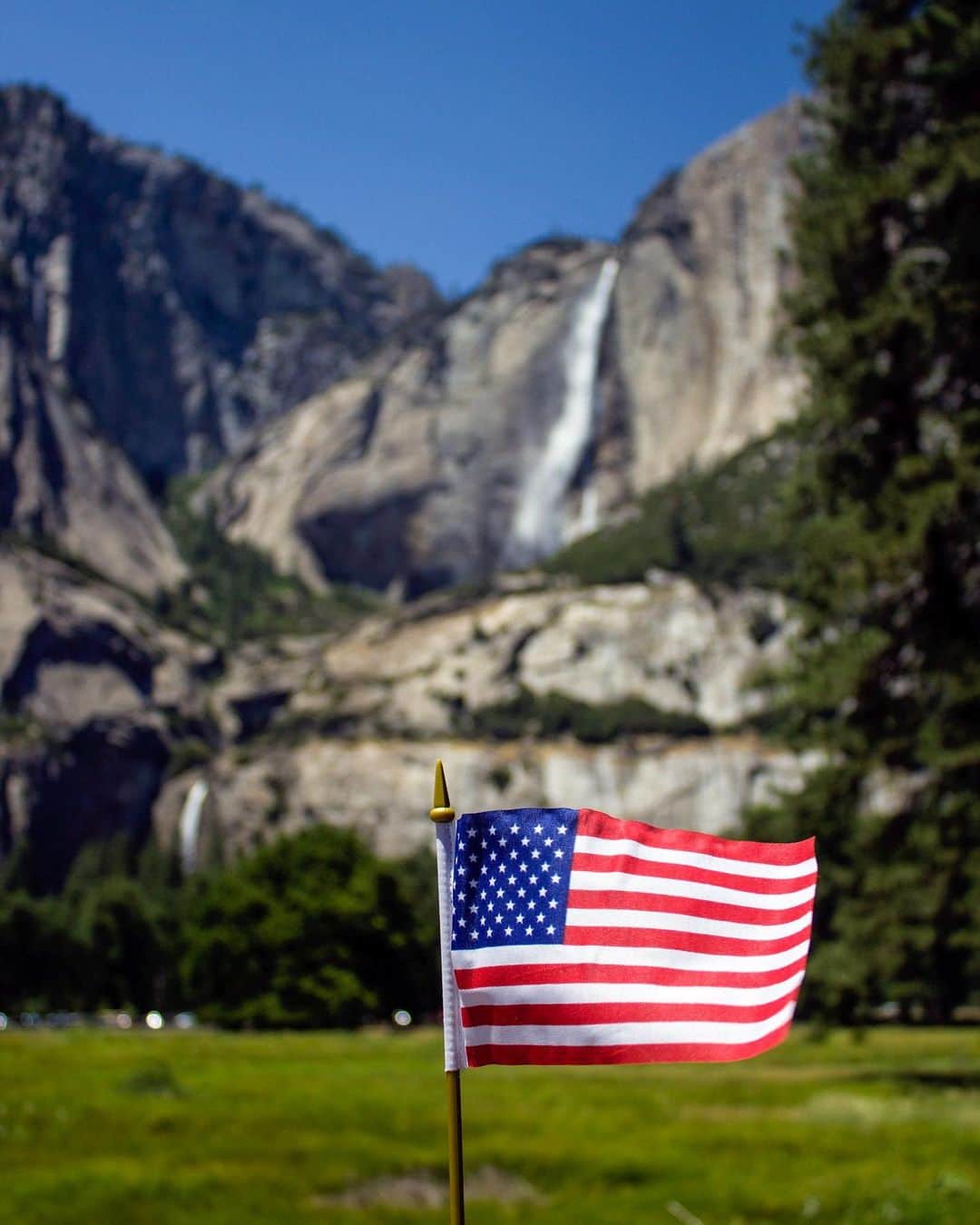 のインスタグラム：「This National Veterans and Military Families Month, we honor and thank active military members, their families and caregivers, and veterans by inviting them to enjoy our public lands for free.    A free lifetime pass is available for veterans of the U.S. Armed Services and Gold Star Families, and a free annual Military Pass is available for current U.S. military members and their dependents.    The passes provide free access to over 2,000 federal recreation areas, including national parks and wildlife refuges.   Interior proudly offers these passes to demonstrate our immense gratitude for those who make enormous sacrifices for our nation. Learn more, link in our bio.   Photo by @yosemitenps   #veterans #militaryfamily   Alt Text: An American flag blows in the wind in front of a large waterfall cascading down a steep and distant cliff.」
