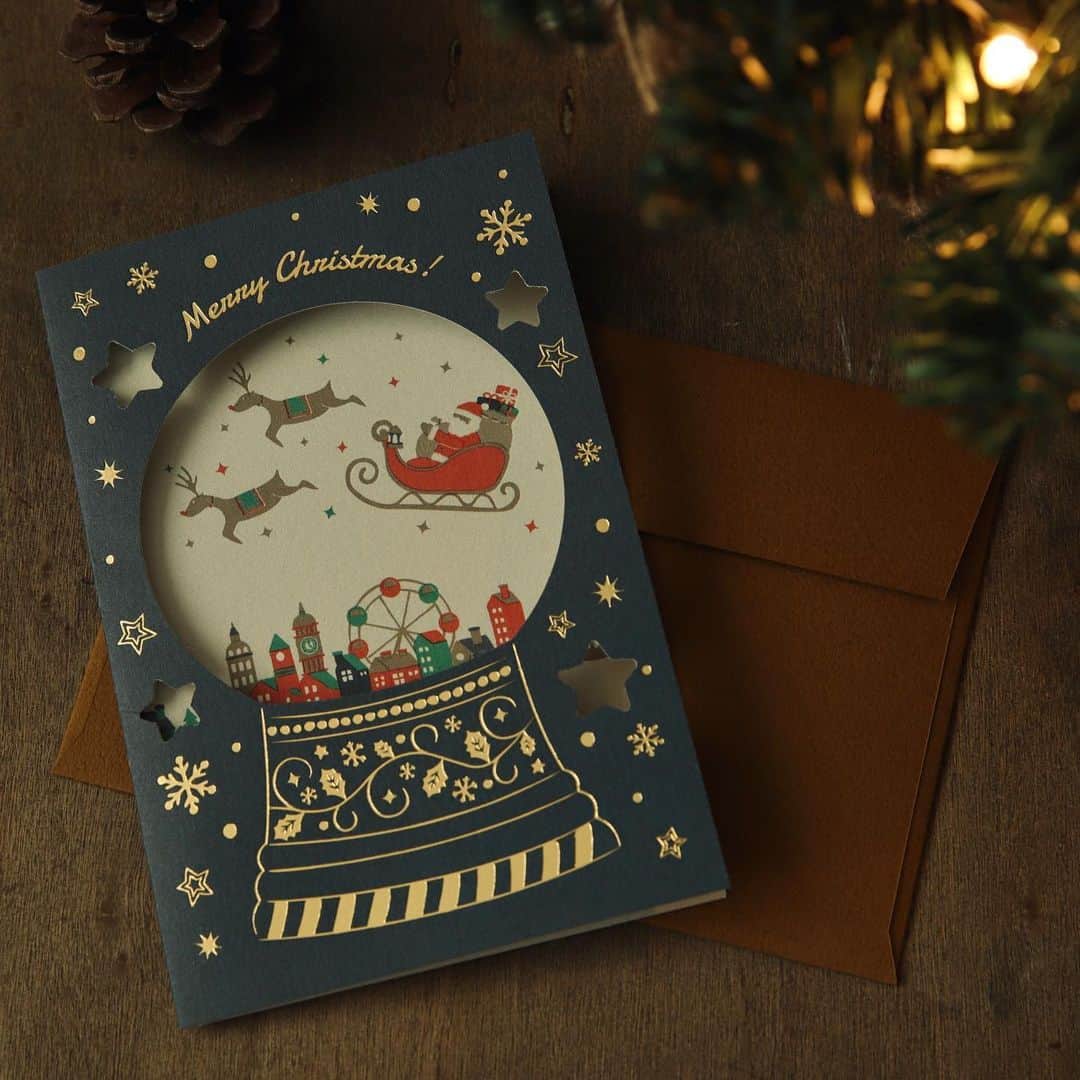 RYU-RYUさんのインスタグラム写真 - (RYU-RYUInstagram)「🎄新商品のお知らせ🎄 . 【クリスマスグリーティングカード】 . こんばんは！ 本日も新商品のクリスマスカードをご紹介します🎅 . スノードームをイメージした クリスマスのグリーティングカードです🎄 . 金箔を贅沢に使用した表紙の型抜き部分からは 内側に印刷されたイラストが覗きます✨ イラストの積もった雪の部分に メッセージを書くこともできます📝 . カードに合わせた色使いの封筒付きで 定型郵便での郵送も可能です📮 . 外国の絵本のようなカードは 受け取った後も 飾っておきたくなる可愛さですよ✨ . 【クリスマスグリーティングカード】 カード1枚/封筒1枚(定形) 本体価格380円＋税 . こちらの商品は リュリュのオンラインショップ 『リュリュマーケット』でも ご購入頂けます😊 プロフィール画面から アクセスしてくださいね🎅 . #ryuryu #リュリュ #雑貨 #ステーショナリー #文具 #クリスマス #クリスマスカード #クリスマスツリー #オーナメント #プレゼント #ミニカード #タグカード #ラッピング #ホログラム #サンタクロース #ギフト #ジングルベル #メリークリスマス #グリーティングカード #グリーティング #スノードーム」11月2日 17時12分 - ryuryu_zakka