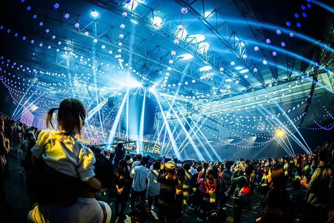 のインスタグラム：「本日より、『えんとつ町の踊るハロウィンナイト』のオンライン配信がスタートします。 　 オンライン配信チケットの販売枚数は既に【８０００枚】を突破しております。  「盆踊り大会のオンライン配信チケット」ってあんまり聞いたことがないですが、クオリティーは僕が約束します。 もうね、とんでもないことになっています。 　 最初から最後まで楽しくて、優しくて、おバカな時間しか流れてないのですが、最後はなんか泣きそうになっちゃう２時間です。 　  内容をお伝えします。 　 まずは、イベントのオープニングがまるっと入っております。 　 会場中央の巨大提灯の一人喋り（えんとつ町のプペルのエピソード・ゼロに触れています）があった後に、映画『えんとつ町のプペル』のオープニングの『Halloween Party』(HYDEさん)のブチアゲ・パフォーフォーマンスがあるのですが、いきなりヤバイです。 　 床からゾンビの腕が数十本出てきて、ステージの上に次から次へとゾンビが上がってきて、ゾンビ史上最速のスピードで踊り狂ってます。 　 観客の歓声を聞いていただければ分かりますが、この一発目のパフォーマンスで幕張メッセはノックアウトされています。 　 その後に、ミュージカル『えんとつ町のプペル』のオープニングナンバーです。 　 こちらは吉原光夫さんが演出をして、国内外で活躍されているKAORIaliveさんが振りを付けてくださったわけですが、これはミュージカル『えんとつ町のプペル 2025』チームですね。 　 キャストもミュージカル『えんとつ町のプペル 2025』に出演が決定しているキャストが務めました。 　 これがまたとんでもないクオリティーで、全舞台関係者が「畜生っ！やられた！」となったと思います。 僕も、あれが別のチームの仕事だったら、強烈に嫉妬していました。  もう、ここだけで料金のもとは取れます。 　 そこから次は、ミュージカル『えんとつ町のプペル』コーナーですね。  こちらはミュージカル『えんとつ町のプペル』の２０２１年公演の振り付けを担当してくださったSHOJINさんが振り付け&演出を手掛けてくださったのですが、これもクオリティーが半端なかったです。 　 『えんとつ町の踊るハロウィンナイト』は大トリのバンドザウルスコーナーで素人オジサンダンサー達が出演してしまうので（そんなの出すなよ！）、ここで確かなクオリティーでバチコンやってもらえると、「もう文句はないでしょ！」と言えるから、すごく助かるんです。 　 「今ので本編は終わりました。バンドザウルコーナーは打ち上げです」と言い逃れることができるから、すごく助かるんです。 　 とにかく、 このミュージカルコーナーがすごく良かった。  最後、サプライズゲストでロザリーナが調子に乗って出てましたけど、アイツも凄いっすね。 　 酒場でウザ絡みしてくるイメージしかなかったのですが、ステージに立つとやっぱり輝いていていて、アイツが「ハロウィンの〜」と歌い出した瞬間に、「生が聴けた〜！」と興奮しちゃったもんな。 　 僕世代だとCHARAさんがそれにあたると思うのですが、ファンタジーを纏っている人（纏える人）って確実にいて、こればっかりは努力ウンヌンじゃなくて「選ばれた人」で、ロザリーナもまた「選ばれた人」なんだと思います。 是非、オンライン配信で確認してください。 　 🏮 ミュージカルコーナーの後は西野の飛び入りステージがありまして、１万３０００人でオーシャンゼリゼを合唱しています。  これはもう笑けるぐらい愛と平和しかありません。  子供から爺ちゃん婆ちゃんまでが一つになって「オ〜、シャンゼリゼ〜」言うとります。  泣くシーンでもないのに泣いてるお客さんもいたのですが、でも、泣いちゃう理由はすごく分かります。「ずっと、こんなに世界を探してた」といったところでしょう。  🦖 その後は、いよいよ『バンドザウルス』です。  バンドザウルスは今回の幕張メッセがデビュー戦だったのですが、なんなら、この日一番の盛り上がりで、この日一番の人気者でした。 巨大提灯が「今夜のトリを飾るのは、バンドザウルスだ！」と名前を紹介した時には、地響きのような歓声が上がって、その瞬間、皆がバカになっていることを確信しました。 　 最高じゃないですか。 　 「中年オヤジが恐竜のかぶりものをしただけのバンドに、１万３０００人が熱狂する」って、もうバカしかいない（笑）。 　 バンドザウルスのパフォーマンスは、もうオンライン配信でご確認ください。 　 最初から最後まで、ず〜っとフザけていて、途中、号泣している梶原さんがステージの下から、せり上がってきて、一曲歌うのですが、よくよく考えたら「ザウルス」でも何でもないのですが、もう何でもアリです。 　 未就学児から爺ちゃん婆ちゃんまで、恐竜バンドに熱狂していました。 　  『えんとつ町の踊るハロウィンナイト』は本当に「ずっと、こんな世界を探してた」というような空間で、是非、ご家族でオンライン配信を見て、子供達に「こんな世界があるんだよ」ということを教えてあげて欲しいです。 　  『えんとつ町の踊るハロウィンナイト』のオンライン配信はプロフィール欄から！」
