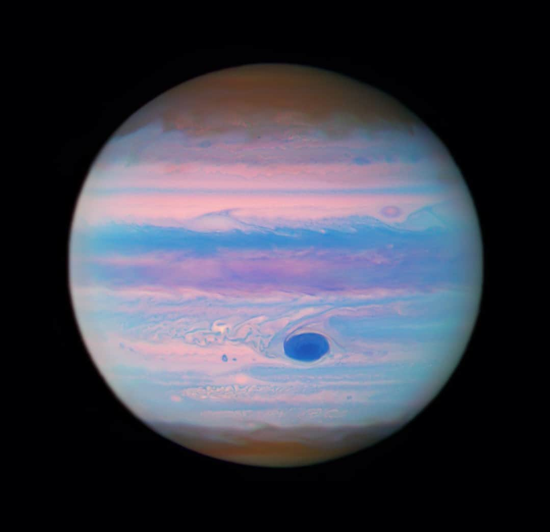 NASAのインスタグラム：「Let’s fast forward 370 million miles later, we see your Great Red Spot in ultraviolet wavelengths.  This new @NASAHubble image was created from data that’s part of a proposal that looked at Jupiter’s superstorm system. The researchers plan to map deep water clouds using the data to define 3D cloud structures in Jupiter’s atmosphere.  Hubble’s ultraviolet-observing capabilities allow astronomers to study the short, high-energy wavelengths of light beyond what the human eye can see.   Image description: The planet Jupiter with its cloud bands seen in shades of pink, rusty red, blue, and purple. The Great Red Spot is a deep navy blue, surrounded by bands and swirls of pink, and light blue.  #IsItOverNow #Jupiter #space #Hubble #spaceimages #astronomy」