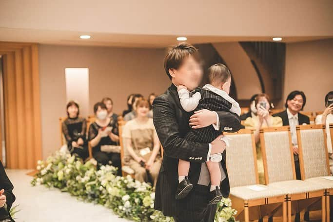 三島ゆかりのインスタグラム：「挙式の写真💒 息子をリングボーイで車に乗せて登場させようかとも考えましたが、夫が抱っこして一緒に入場したいと言ったのでそうしました❤️🤵‍♂️ 私にはお父さんがいないのでバージンロードはおじいちゃんと一緒に👰‍♀️ おじいちゃんが「ゆかりの結婚式が終わるまでは生きとかな！」ってずっと言ってくれてて嬉しかった✨ 今も元気に生きてくれてるけど💕👴ww  お母さんにベールダウンしてもらう時、いってらっしゃいって言われてちょっと泣きそうやったけど息子がグズってたのもあって泣かずに留まりました🥹 それにさちがなんせ泣きすぎてて、それ見て逆に笑いそうでしたww😂 誓いの言葉とかの時もきゅんがギャン泣き寸前で、お母さんに抱っこしてもらってたけど(牧師さんの方を私は見てるから背を向けてるけど)あー泣いとる泣いとると思ったら笑っちゃって🤣 なので前の投稿でも書いたように、厳かなチャペルでもほっこり温かい結婚式になったな〜と💗👶  誓いのキスはファミリー婚ならではのサンドウィッチキスにしました💏 まぁギャン泣きの全力拒否やったけどねwww それもまたいい思い出です💋 最後に笑かしてくれたんが私と夫共通の友達で会場で1番ふざけてた奴😂😂😂 いや〜俺ミスったなぁ思って焦りました〜！言うてたけどめっちゃオモロかったから最高でした👍👍👍 そりゃカメラマンさんもバッチリ撮るよね📸😎  参列してくださった皆様、遠方からも来てくださり、あいにくの雨でお足元も悪い中、本当にありがとうございました🥺🥺🥺 結婚式の投稿、まだまだ続きます🤭🍎  #結婚式 #チャペル #挙式 #教会式 #ファミリー婚 #バージンロードはおじいちゃんと #ベールダウン #感謝 #感動 #ギャン泣き #かわいい #サンドウィッチキス #やりたかったやつ #ありがとう #2023春婚 #ウェディングドレス #新郎新婦 #楽しかった #来てくださった皆様ありがとうございました #三島ゆかり #卒花」