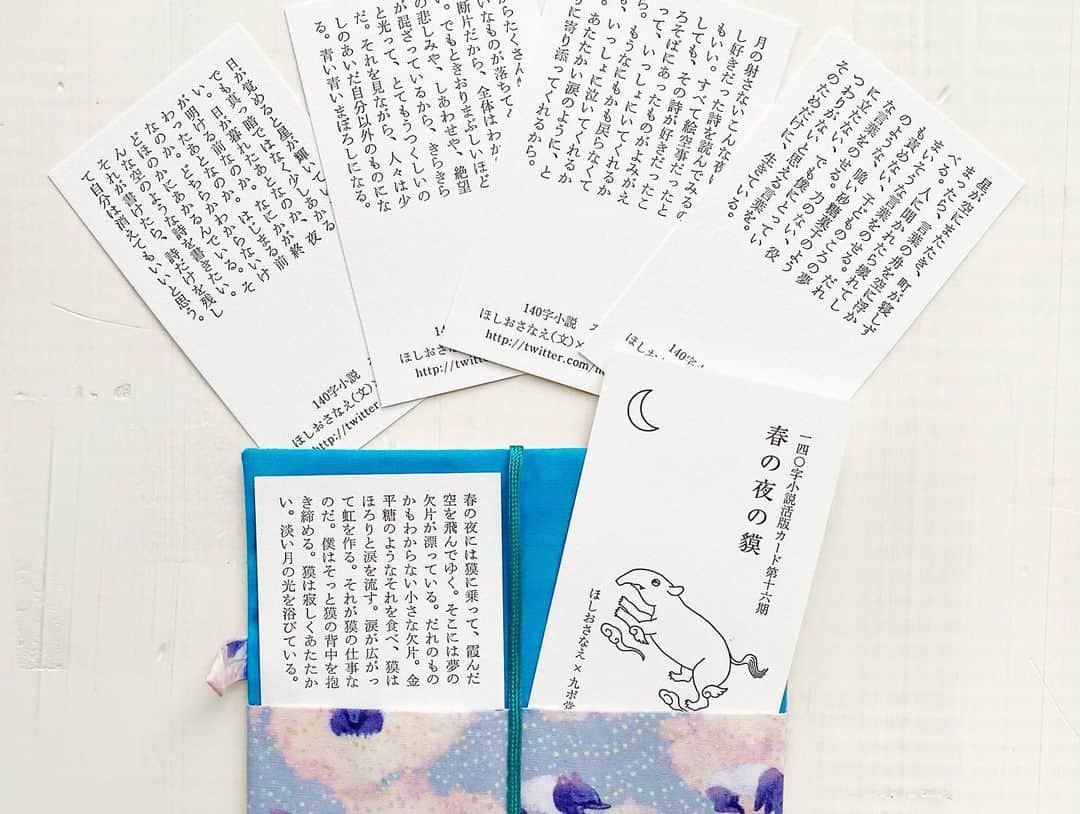 ほしおさなえのインスタグラム：「140字小説活版カード「春の夜の獏」の予約販売を開始しました。  活版印刷と表紙のイラストは九ポ堂によるもの。ひとりで綴った言葉を舟にのせ、夜空に浮かべる。夢を食べる獏の背中に乗って空を旅する。思いを言葉にのせること、それをだれかに届けることにまつわる物語５編を集めました。  特装版の布ケースは、テキスタイルデザイナー・ヌイヌイトコネコネがこの特装版のために作成した獏柄の布製。虹と金平糖が散らばる空に獏たちが浮かぶファンタスティックな布を手作業でブックカバー型のケースにしました。本を真似てスピンもついていて、閉じてボタンで留められる凝った作りです。  特装版はキラキラの銀の箔押しが施された白い紙箱入り。マッチ箱のように引き出すと、特装版が開かれた形ではいっています。マスキングテープは特装版の布と同柄です。どこを取ってもかわいいバクちゃんがあらわれるようになってます。  特装版、通常版、マスキングテープとも、11月11日（土）開催の #文学フリマ東京37 で発売です。会場にお越しになれない方は、ぜひ予約販売をご利用ください。お届けは #文学フリマ東京 終了後、11月13日（月）以降になります。よろしくお願いします！  https://hoshiosanae.stores.jp」