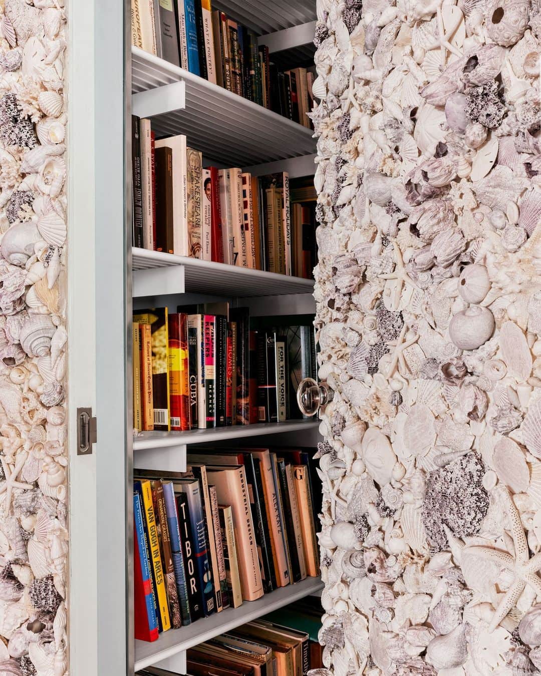 のインスタグラム：「Seashell-encrusted wall or secret Narnia door? On its own, the adorned wall of this Miami Beach residence is something to behold, but upon further investigation, the wall opens up to a hallway of books leading to a steel-clad screening room—a tribute to Gae Aulenti’s 1970s apartment in the Palazzo Pucci. “We wanted to evaporate the hallway, so you enter through a clouded sunset,” says Andre Herrero, who designed this apartment alongside his partner Adam Charlap Hyman via their firm Charlap Hyman & Herrero (@ch_herrero).   Click the link in bio for the full tour of this Miami beach home. Written by @cokhio. Styled by @tessawatson. Photographed by @chrismottalini.」