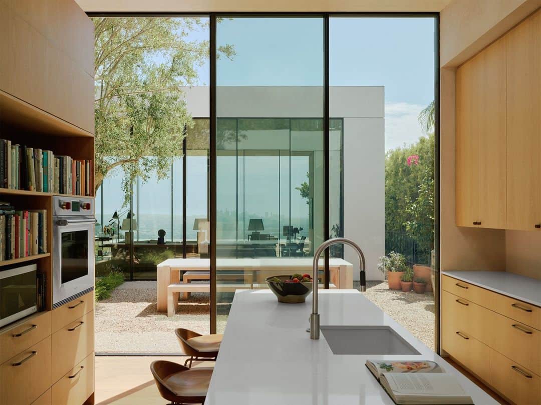ELLE DECORのインスタグラム：「“You don’t want the architecture and interior design competing with each other,” says the owner of this ethereal Los Angeles house. Which is why he hired architects Brett Woods and Joseph Dangaran (@woods_dangaran) and ELLE DECOR A-List firm Studio Mellone (@studiomellone) for the job. The result is vision of glass planes intersected by velvety plaster walls. Here from the kitchen, you can see straight through to a courtyard and the living room beyond.   Click the link in the bio to tour the rest of this Hollywood Hills house, as featured in our November 2023 issue. Written by @isuredontknow. Styled by @amykchin. Photographed by @william.jess.laird.」