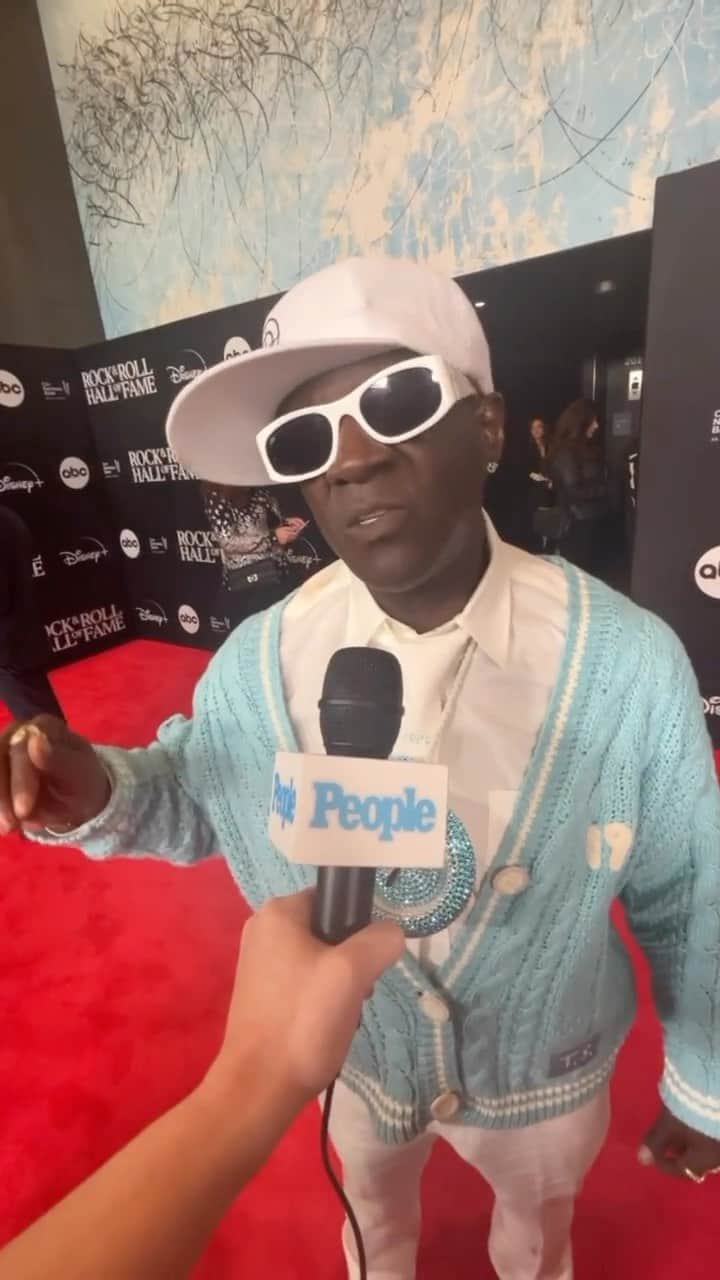 People Magazineのインスタグラム：「Flavor Flav’s signature clock necklace is never going out of “Style” — and neither is his love for Taylor Swift. 🩵 The Public Enemy founding member wore his signature timepiece while wearing a matching cardigan from Swift’s website at the Rock & Roll Hall of Fame ceremony Friday night!  More on this in our bio link!」