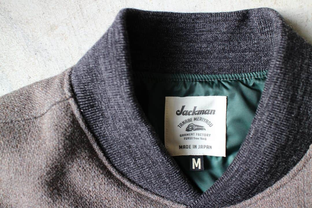 Jackmanのインスタグラム：「▽ FW23 MELTON AWARD JACKET JM8380 70%WOOL 20%POLYESTER 5%NYLON 5%ACRYL ¥46,200 Color:38Sepia  経糸のみを2重にした 珍しい二重織りメルトン素材を使用した アウォードジャケットです  多色織りのためシャトル織機ではなく レピア織機を使用して 奥行きのある色合いを 生地で表現しました  ウール織り生地は本来 洗いと縮絨により 独特の膨らみがある表情に仕上げますが このアウォードジャケットは 1900年代初頭の クラシカルな表情にするため 縮絨をせず柔らかみのない 油分が抜けた風合いにしました  デザインは ゆったりしたシルエットに ボリューム感のある2枚袖 衿リブはコンパクトなシングルタイプの Baseball仕様です  中綿が入っていない分 裏地には防風性の高い 高密度タフタを使用  厚手のインナーも無理なく着用できる 工夫をしました  The Award Jacket features a rare double-woven melton fabric with only the warp having two layers. For multicolor weaving, a rapier loom was used instead of a shuttle loom to express the deep colors in the fabric. While typical wool fabric is finished by washing and fulling it to provide its unique texture and fullness, we omitted the fulling so that the jacket would lack softness and be oil-free to achieve a classic look reminiscent of the early 1900s. The design features a relaxed silhouette, voluminous double sleeves, and a compact single-rib collar like they use in baseball. While there is no padding, we used high-density taffeta lining for the backing to provide wind protection. We also made accommodations to allow for the thick inner layers to be worn comfortably.」