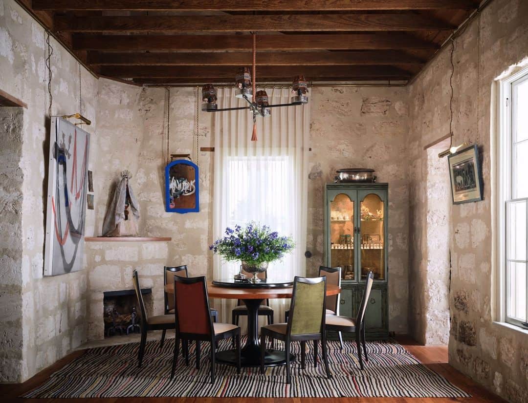 ELLE DECORのインスタグラム：「When designing this San Antonio home, architect @lakeflato’s Vicki Yuan was tasked with the challenge of figuring out how to display her client’s oddities—Mexican Santos, Maasai beads, a collection of seashells, as well as the scores of paintings and photographs by local artists. Yuan found a solution in a gleaming brass picture rail that traces the perimeter of the house. The move allows the homeowner to change the arrangement as she pleases, without having to drill holes into the historic caliche stone walls. Today the room, with its lofty exposed ceilings and its artfully hung works, feels like a Lone Star state version of an 18th-century salon.   Click the link in bio for the full tour of this eclectic Texas home. Written by @anna_fixsen. Photographed by @douglasfriedman. Styled by @jennyoconnorstudio.」