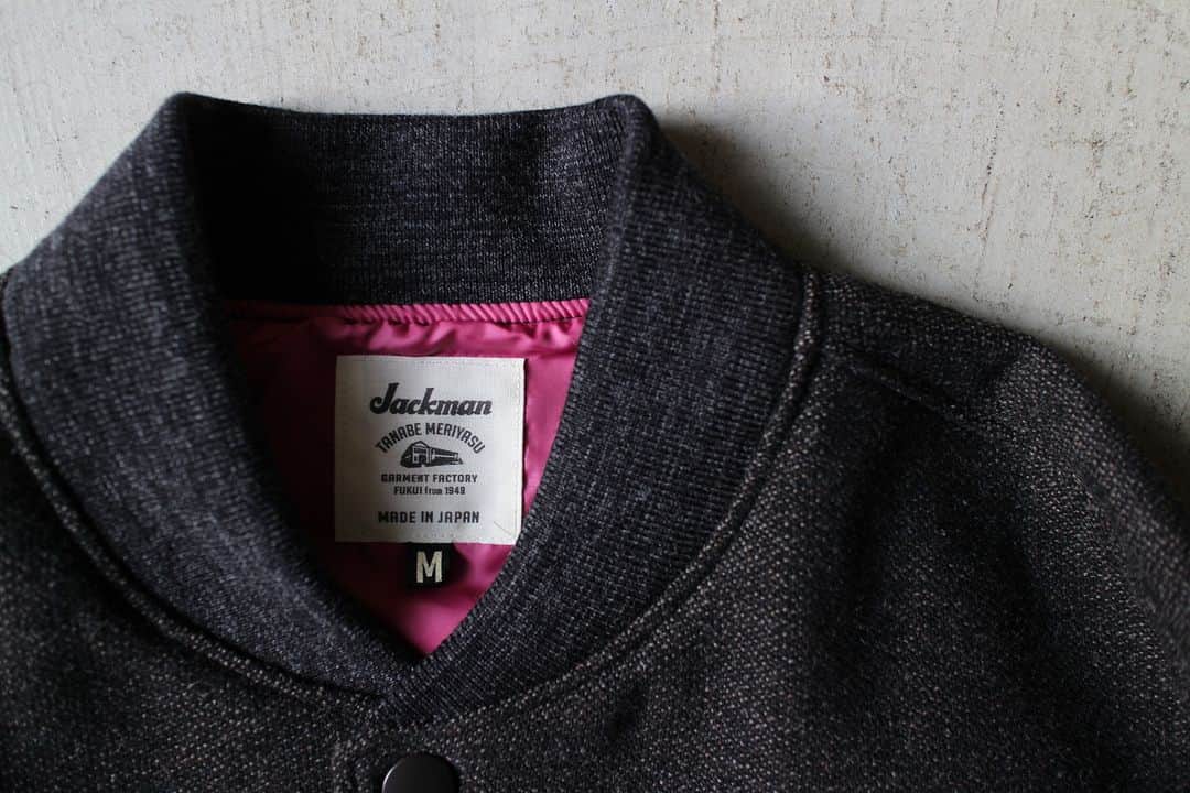 のインスタグラム：「▽ FW23 MELTON AWARD JACKET JM8380 70%WOOL 20%POLYESTER 5%NYLON 5%ACRYL Color:87Black Mix  経糸のみを2重にした 珍しい二重織りメルトン素材を使用した アウォードジャケットです  多色織りのためシャトル織機ではなく レピア織機を使用して 奥行きのある色合いを 生地で表現しました  ウール織り生地は本来 洗いと縮絨により 独特の膨らみがある表情に仕上げますが このアウォードジャケットは 1900年代初頭の クラシカルな表情にするため 縮絨をせず柔らかみのない 油分が抜けた風合いにしました  デザインは ゆったりしたシルエットに ボリューム感のある2枚袖 衿リブはコンパクトなシングルタイプの Baseball仕様です  中綿が入っていない分 裏地には防風性の高い 高密度タフタを使用  厚手のインナーも無理なく着用できる 工夫をしました  The Award Jacket features a rare double-woven melton fabric with only the warp having two layers. For multicolor weaving, a rapier loom was used instead of a shuttle loom to express the deep colors in the fabric. While typical wool fabric is finished by washing and fulling it to provide its unique texture and fullness, we omitted the fulling so that the jacket would lack softness and be oil-free to achieve a classic look reminiscent of the early 1900s. The design features a relaxed silhouette, voluminous double sleeves, and a compact single-rib collar like they use in baseball. While there is no padding, we used high-density taffeta lining for the backing to provide wind protection. We also made accommodations to allow for the thick inner layers to be worn comfortably.」