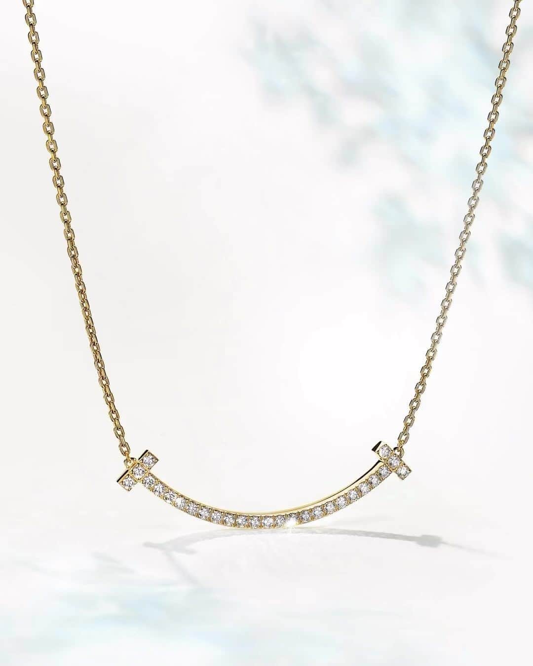 ティファニーのインスタグラム：「This holiday, a dazzling new chapter begins with an unexpected curve. Inspired by the universal gesture for happiness, this Tiffany T smile pendant features our sleek House motif traced in hand-set round brilliant diamonds. Link in bio. #ATiffanyHoliday #TiffanyT #TiffanyAndCo」