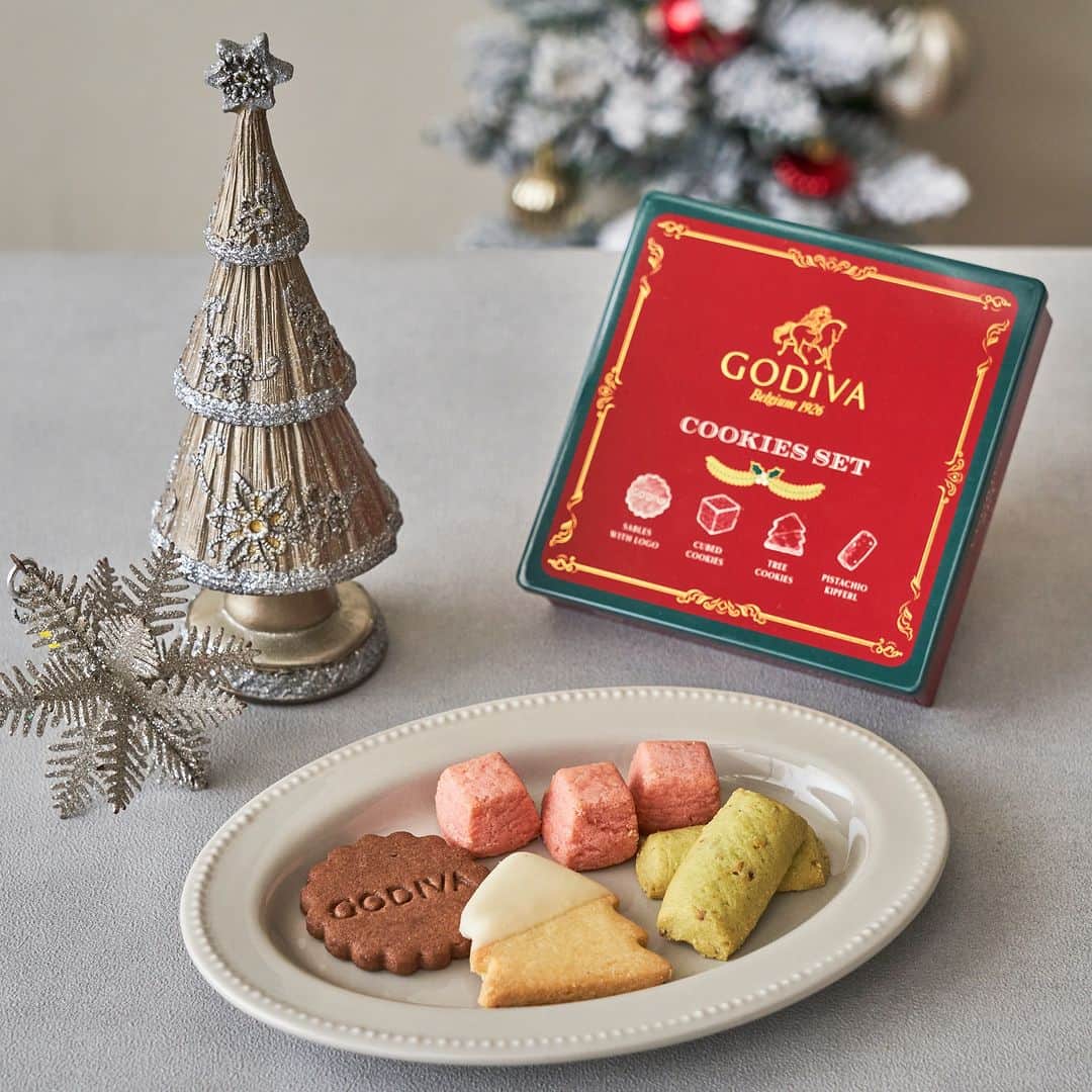 GODIVAのインスタグラム：「ホリデーシーズンのプレゼントにゴディバのクッキーはいかがですか？🎄  雪の積もったもみの木をかわいらしく模した「ツリークッキー」や、 ほろっとほどける食感の、ドイツやオーストリアの伝統的なお菓子キッフェルにピスタチオパウダーやピスタチオダイスを加えて焼き上げた「ピスタチオキッフェル」など、クリスマス感たっぷりのクッキーの詰め合わせです🍪  パッケージは赤をメインに、柊のワンポイントでクリスマスらしく華やかに仕上げました！ 是非、大切な人へのクリスマスプレゼントやクリスマスパーティーのお土産にお選びください✨  ==【商品詳細】================================= ■「クリスマス クッキーセット」 ■販売期間：2023年11月1日（水）～ ■取扱店： 全国のゴディバショップ、GODIVA café、ゴディバ オンラインショップ ==============================================  #ゴディバ #GODIVA #クリスマス #クッキー #クリスマスプレゼント #クリスマススイーツ #チョコレート好き」