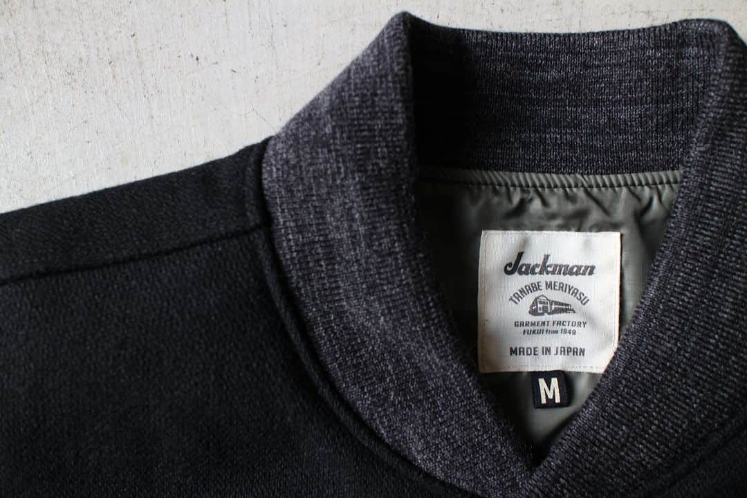 のインスタグラム：「▽ FW23 MELTON AWARD JACKET JM8380 70%WOOL 20%POLYESTER 5%NYLON 5%ACRYL Color:07Black   経糸のみを2重にした 珍しい二重織りメルトン素材を使用した アウォードジャケットです  多色織りのためシャトル織機ではなく レピア織機を使用して 奥行きのある色合いを 生地で表現しました  ウール織り生地は本来 洗いと縮絨により 独特の膨らみがある表情に仕上げますが このアウォードジャケットは 1900年代初頭の クラシカルな表情にするため 縮絨をせず柔らかみのない 油分が抜けた風合いにしました  デザインは ゆったりしたシルエットに ボリューム感のある2枚袖 衿リブはコンパクトなシングルタイプの Baseball仕様です  中綿が入っていない分 裏地には防風性の高い 高密度タフタを使用  厚手のインナーも無理なく着用できる 工夫をしました  The Award Jacket features a rare double-woven melton fabric with only the warp having two layers. For multicolor weaving, a rapier loom was used instead of a shuttle loom to express the deep colors in the fabric. While typical wool fabric is finished by washing and fulling it to provide its unique texture and fullness, we omitted the fulling so that the jacket would lack softness and be oil-free to achieve a classic look reminiscent of the early 1900s. The design features a relaxed silhouette, voluminous double sleeves, and a compact single-rib collar like they use in baseball. While there is no padding, we used high-density taffeta lining for the backing to provide wind protection. We also made accommodations to allow for the thick inner layers to be worn comfortably.」
