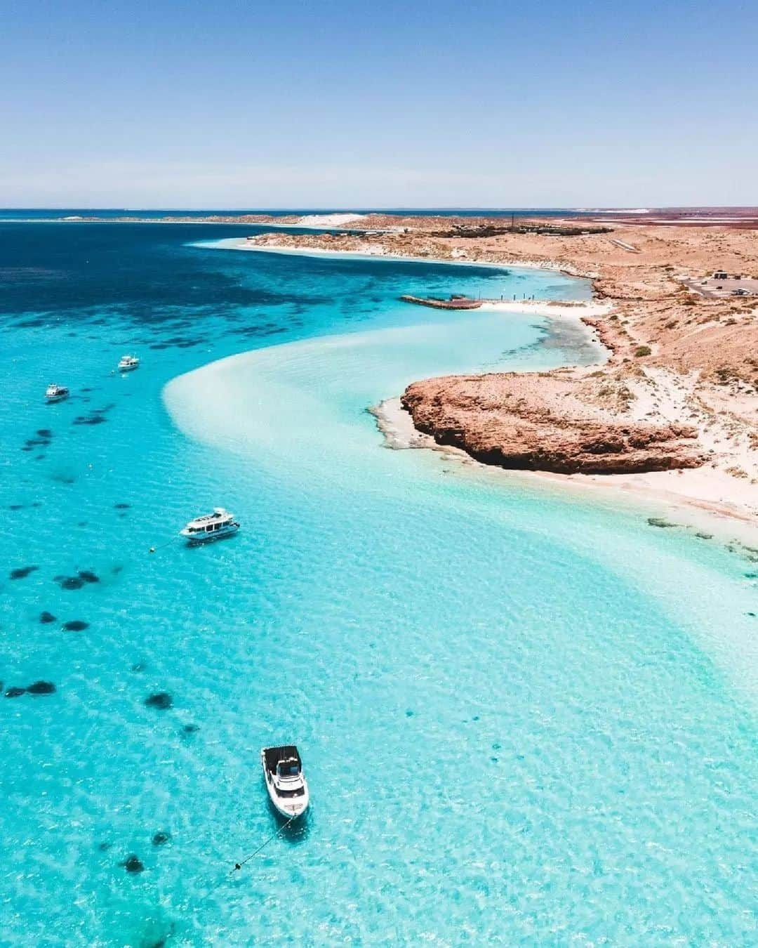 Australiaのインスタグラム：「There's a million reasons to fall in love with #CoralBay, but here's one more 😚💙 @sebs.views has us mesmerised with this stunning shot of @australiascoralcoast. Nestled near #Exmouth in @westernaustralia, this picture-perfect bay is just about as idyllic as its name suggests. Spend your time relaxing on the white sandy shores or in the clear blue waters snorkelling the @UNESCO World Heritage-listed Nyinggulu (@ningalooreef), just metres from the beach.   #SeeAustralia #ComeAndSayGday #AustraliasCoralCoast #VisitNingaloo #WATheDreamState  ID: boats are anchored in turquoise waters, close to a rocky, sandy coast. The sky above is blue.」