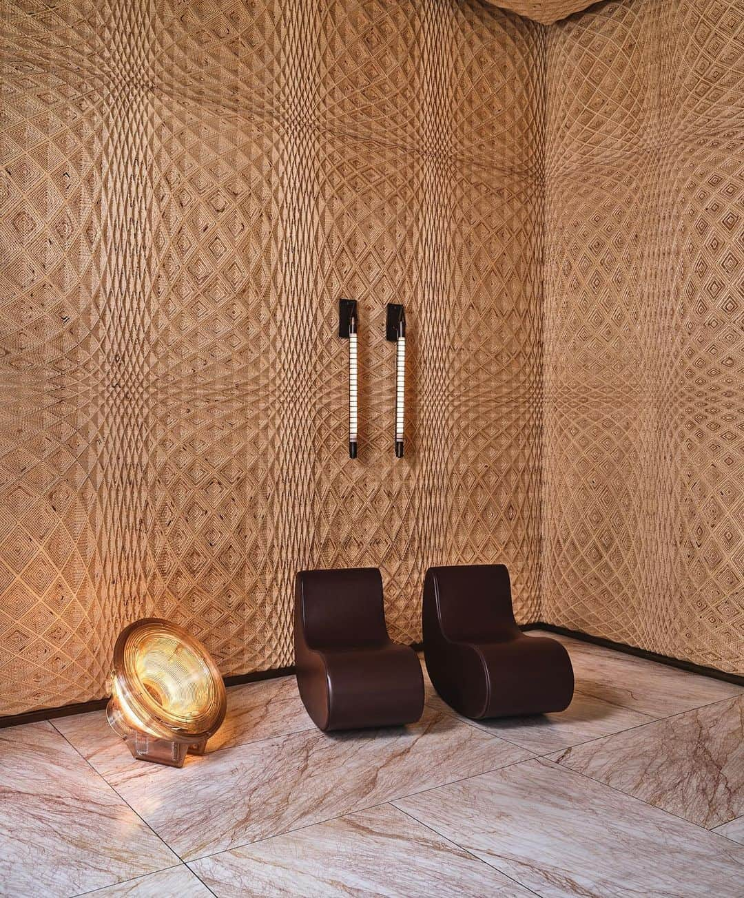 ケリーウェアスラーのインスタグラム：「IDIOSYNCRATIC INTERIOR In crafting the entrance vestibule for @austinproperhotel residential component, we aimed for a more minimalist modern appeal. The wall is a testament to the power of craftsmanship... Laser-cut plywood in a custom pattern, infuses a sense of artful intrigue, creating a captivating optical illusion. The space is subtly lit by a Satellite Lamp by Kooij. Adding character, a vintage 1980s bench features sculpted leather seat pads reminiscent of a horse's saddle... a subtle nod to the Texan locale. XK」