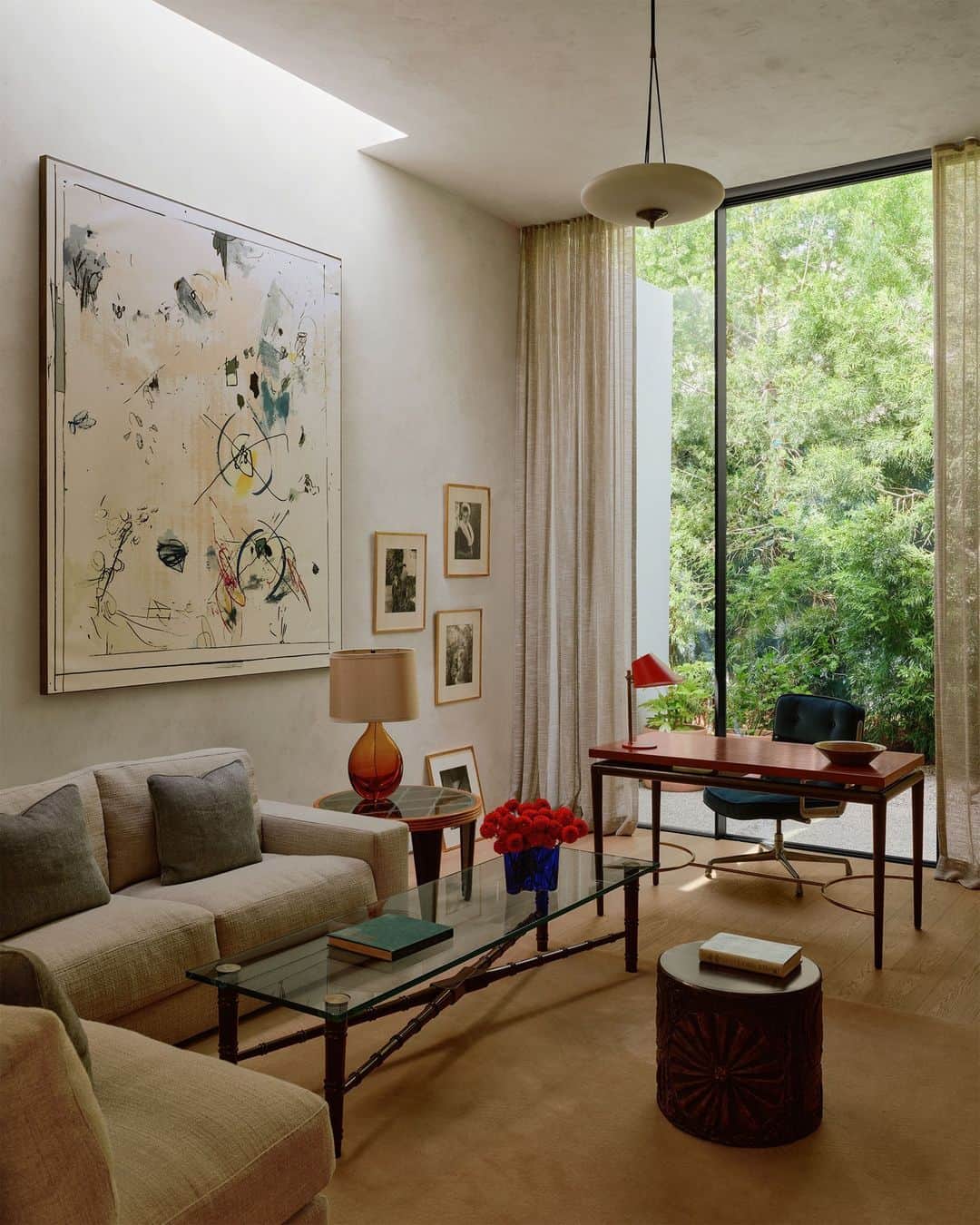 ELLE DECORのインスタグラム：「Clocking in from this home office with a view. In this Hollywood Hills house, architects Brett Woods and Joseph Dangaran of Woods + Dangaran (@woods_dangaran) used clever compositional elements to visually divide the grander proportions into something intimate. New York–based interior designer Andre Mellone of Studio Mellone (@studiomellone) topped it off with a @stilnovoofficial pendant, a William Haines cocktail table, and artwork by @secundinohernandez.  Click the link in the bio to tour the rest of this glass house, as featured in our November 2023 issue. Written by @isuredontknow. Styled by @amykchin. Photographed by @william.jess.laird.」
