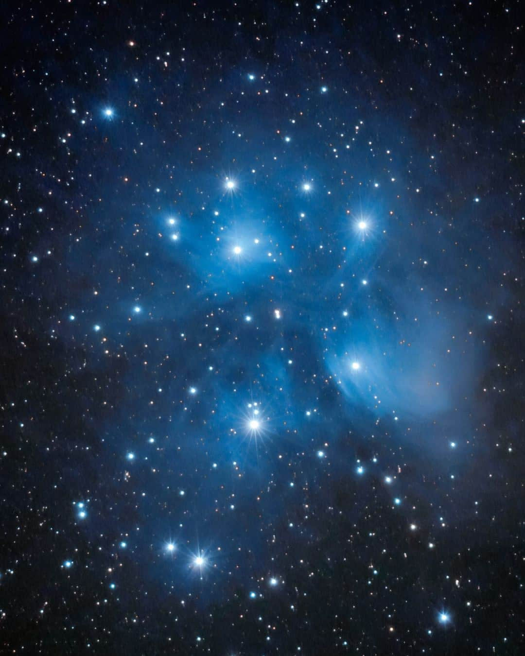 ナショナルジオグラフィックのインスタグラム：「Photos by @babaktafreshi | A close-up image of the Pleiades reveals the hidden beauty of this well-known open star cluster. While the unaided eye can usually detect six or seven stars, there are more than a thousand identified stars in the cluster. I still remember the moment in the 1990s when I saw it for the first time through a telescope, a world of glittering diamonds. This single six-minute exposure using a 600mm telephoto lens also shows the dusty nebula that reflects the blue light of the hot, young stars. Studies show that the sun was once inside a similar star cluster in its childhood, about four billion years ago.   Swipe to see a wider-angle image of the Pleiades rising with the rest of the constellation Taurus in the autumn sky. Also known as the Seven Sisters cluster, it is "Parvin" in Persian, "Thuraya" in Arabic, "Subaru" in Japanese, and "Mao" in Chinese. The Pleiades star cluster features in folklore, literature, and mythology. It appears in the 17,000-year-old paintings in France’s Lascaux Cave and on the 3,600-year-old Bronze Age Nebra sky disk in Germany. It was a calendar mark for ancient astronomers, being close to the point of the vernal equinox in the sky, about 4,000 years ago. It appears on several Sumerian cylinder seals of that era.」