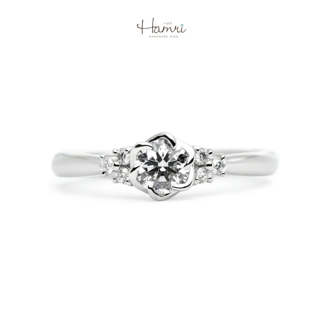 結婚指輪・婚約指輪『Hamri(ハムリ)』のインスタグラム：「【手作り婚約指輪】  まるでブーケのような輝きを束ねたデザイン 愛する人へ想いを込めて。  メイン素材はプラチナ（Pt900)、 ストレートなアームのサイドには センターストーンを引き立てるように 小さなメレダイヤモンドが3石ずつ丁寧にお留めしております。  センターダイヤモンドはお花のようにみえる留め方をしております。 華やかで可憐な、とても素敵な指輪が完成いたしました。  この指輪のように永遠に輝く未来が訪れますように  ご婚約おめでとうございます！  ==========================  ♦︎♢指輪制作の写真や動画を無料撮影、全データプレゼント♢♦︎  DMやLINEでのご相談お待ちしております♥ @hamri_omotesando  ❁・❁・❁・❁・❁・❁・❁・❁・❁・❁・❁  ＊結婚指輪・婚約指輪セットリング5%OFF＊  @hamri_omotesando  Hamri「ハムリ」  〒150-0001 東京都渋谷区神宮前5-11-11 2F  tel 0120-121-175 hp https://hamri.jp/  open 11:00〜19:00 close 火/水　祝日営業  ❁・❁・❁・❁・❁・❁・❁・❁・❁・❁・❁  #手作り婚約指輪 #婚約指輪 #マリッジリング #エンゲージリング #プレ花嫁 #Hamri #Hamri表参道 #オーダーメイドリング #鋳造 #ブライダルリング #ペアリング #プロポーズリング #プラチナリング #ダイヤモンドリング  #2023wedding  #2024wedding #2023秋婚 #2023冬婚 #プレ花嫁準備 #プレ花嫁と繋がりたい #結婚指輪探し #結婚指輪選び #結婚準備  《Hamri検索タグ》  #Hamriデザイン #Hamri指輪作り #Hamri花嫁」