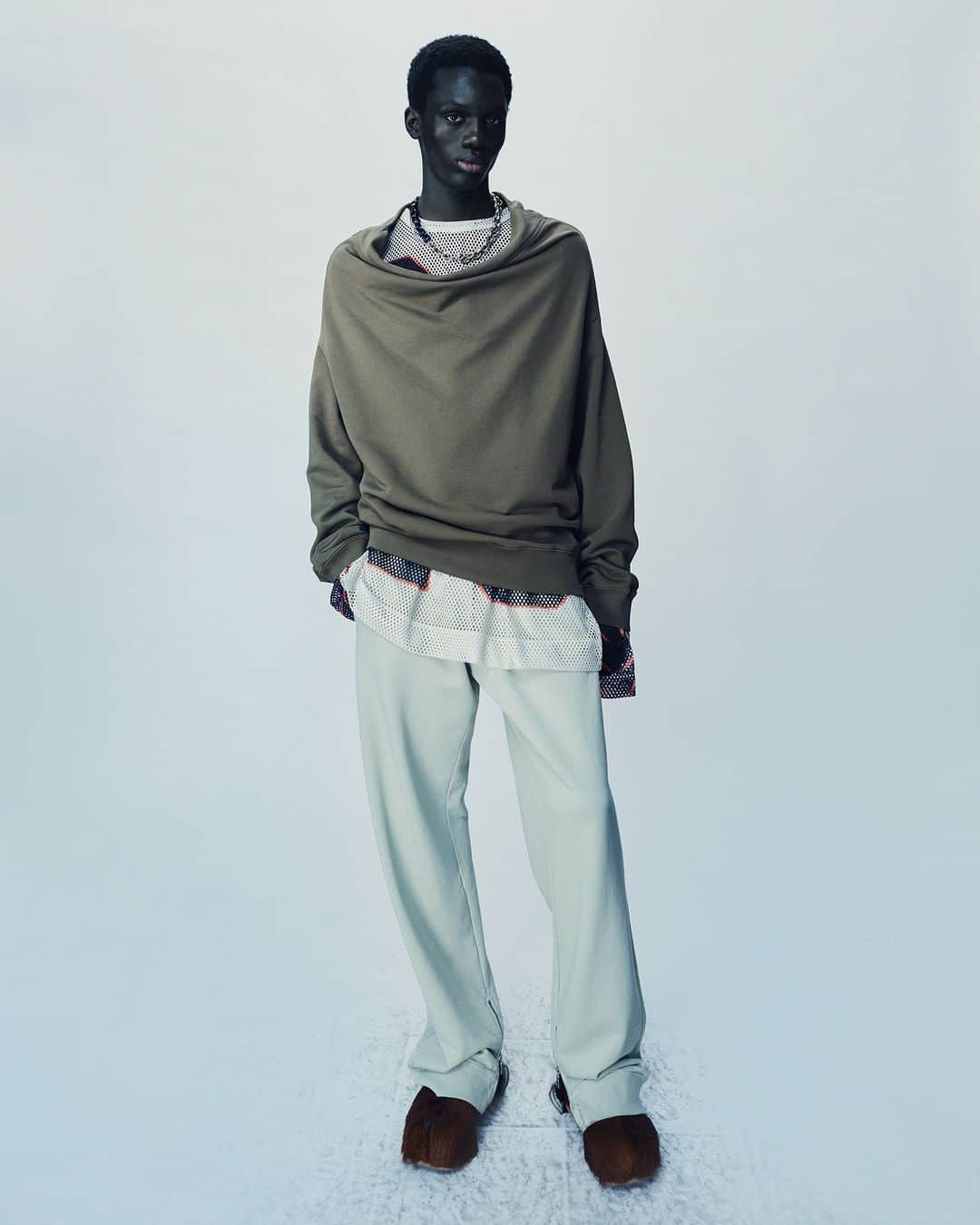 ドリス・ヴァン・ノッテンのインスタグラム：「MEN AUTUMN WINTER 2023  Hamaan wears look 49  Oversized reversed sweatshirt with ribs. Oversized long sleeve mesh t-shirt with digital printed motifs. Straight leg pants with drawstring and rib zip cuffs. Clogs in leather-trimmed calf hair  The collection is available in stores and on driesvannoten.com  #DriesVanNoten #DVNAW23」