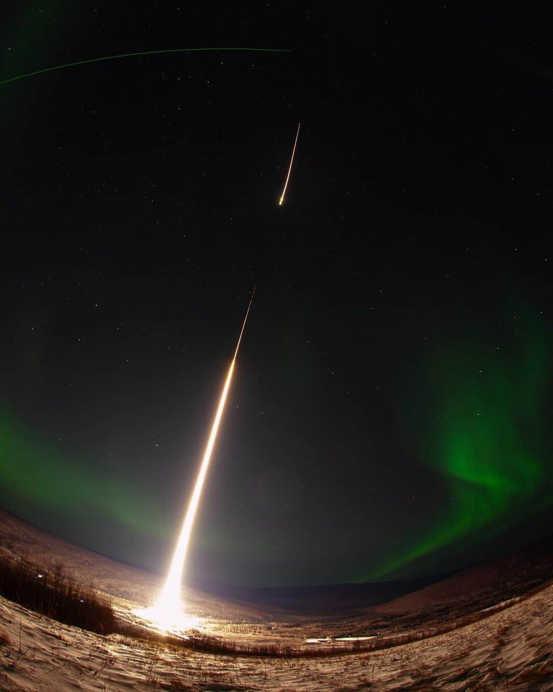 NASAのインスタグラム：「Twice the launches, twice the fun! Two sounding rockets launched from Poker Flat Research Range in Fairbanks, Alaska this week. Yesterday's rocket carried @nasagoddard's DISSIPATION mission into an aurora to study understand how auroras heat the atmosphere and cause high-altitude winds.  Image 1: A long-exposure photograph of a sounding rocket launching into a night sky highlighted by aurora. The sounding rocket is a bright white streak, leaving from a snow-covered ground and moving from bottom left to upper right. A small break in the streak represents the first stage of the rocket burning out and the second stage igniting. A soft, green aurora frames the edges of the image, with many white stars speckled through the black sky. A bright green line toward the top of the frame is a lidar beam. A fisheye lens was used for the photograph, creating a curve for the ground and lidar beam.  Image 2:  A long-exposure photograph of a sounding rocket launching into a cloudy night sky. The sounding rocket is a bright white streak, leaving from a snow-covered ground and moving from bottom left to upper right. The ground is snow covered in the bottom of the frame with and at the right of the frame is a photographer setting up two camera tripods.  Photo Credit: NASA/Lee Wingfield  #Aurora #NASA #SoundingRocket #RocketLaunch」