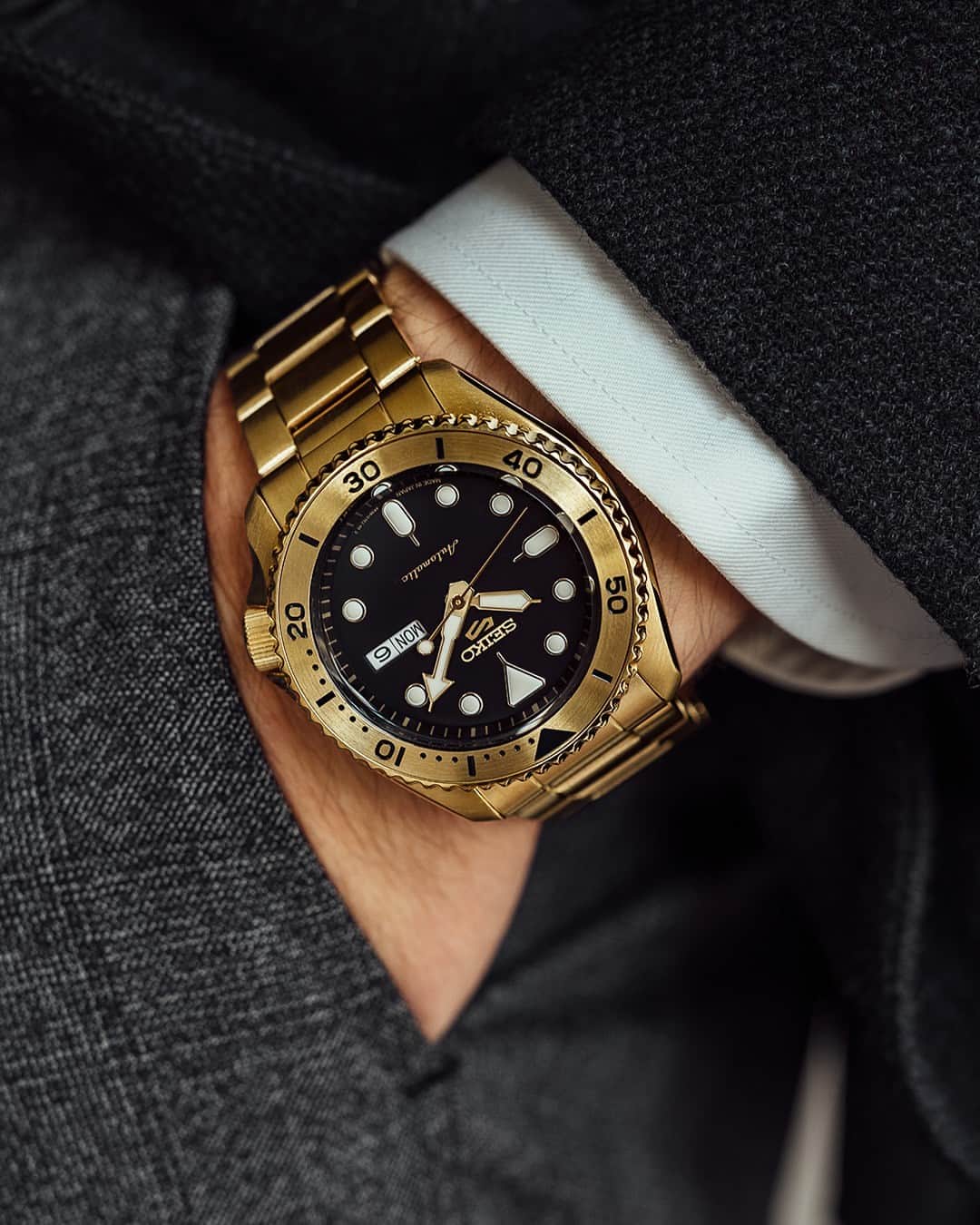 Seiko Watchesのインスタグラム：「Adding Richness to Your Look 💰 - This stylish U.S. Special Creation delivers all-day versatility with a cutting edge. Framed by a gold-tone uni-directional rotating elapsed timing bezel, the black dial features luminous hands and markers, and a date/day calendar. Give the perfect finish to your timepiece game with #SRPK18   #Seiko #Seiko5Sports #ShowYourStyle」