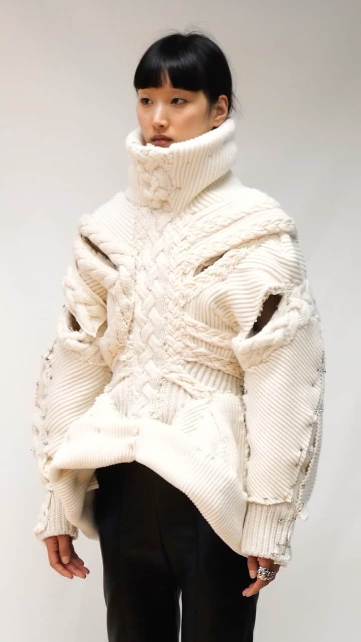 アレキサンダー・マックイーンのインスタグラム：「The Design Team uses a mix of techniques, combining engineered ivory knit cables and rib-knit with slashes. Together, they create a cinched, cocoon-sleeved silhouette that resembles human anatomy.  See the process captured inside the #McQueenAtelier.  Discover #McQueenAW23 via the link in bio.  Music Director: John Gosling Track: Landing by Rob Lewis」