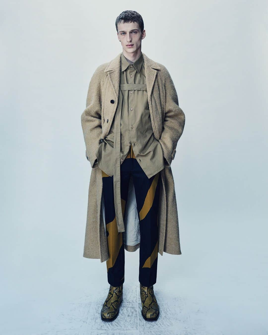 ドリス・ヴァン・ノッテンのインスタグラム：「MEN AUTUMN WINTER 2023  Vasko wears look 8  Loose fit coat with hairy rustic wool. Loose fit shirt in Japanese cotton gabardine with strap on the front part. Tailored pants with screenprinted motifs. Leather chelsea boots.  The collection is available in stores and on driesvannoten.com  #DriesVanNoten #DVNAW23」