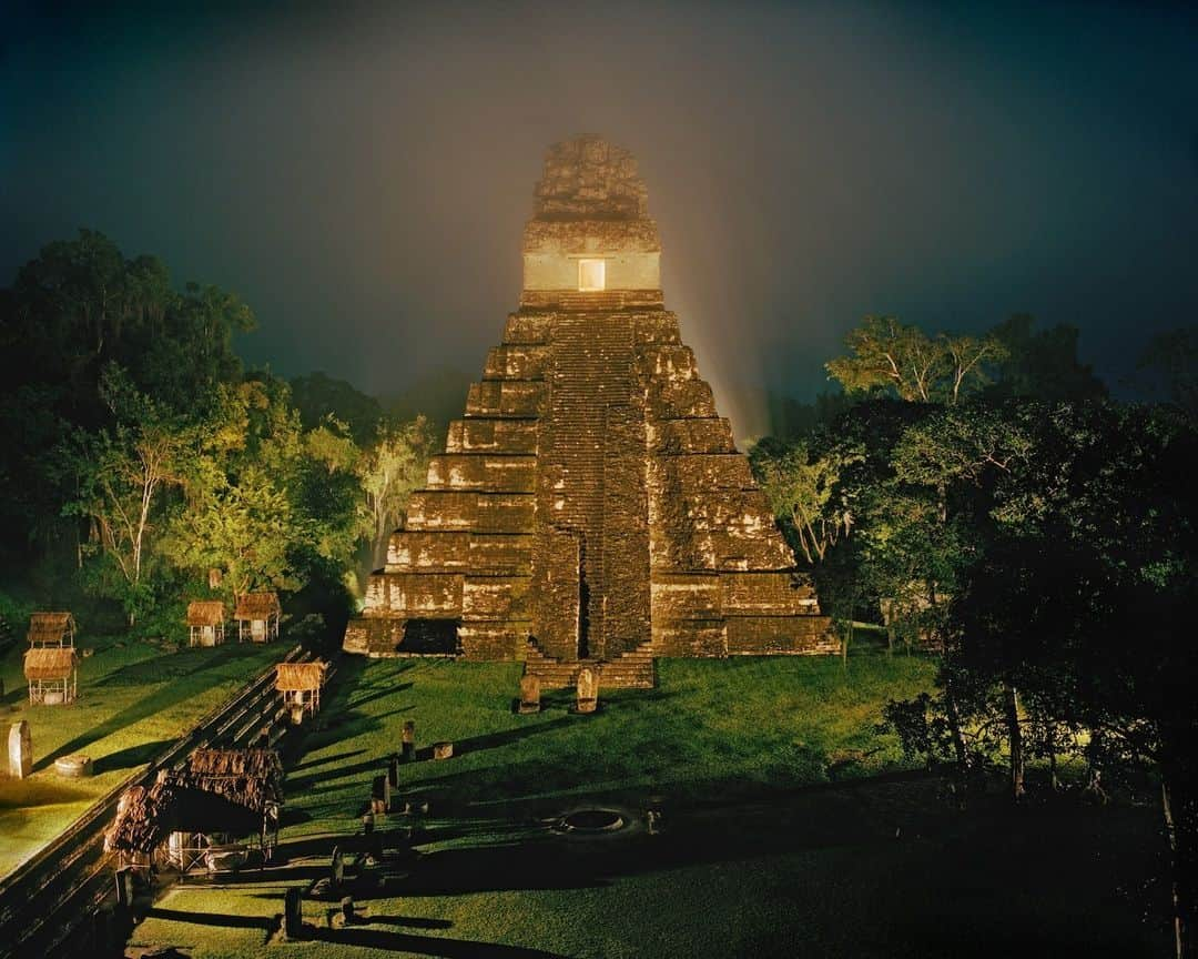 National Geographic Travelのインスタグラム：「Photo by @simonnorfolkstudio | Tikal stands as one of the largest pre-Columbian sites. It is located in the archaeological region of the Petén Basin in what is now Guatemala. The ruins lie in the tropical rainforests that formed the hearth of lowland Maya civilization. Tikal reached its peak during the Classic period (200 to 900 C.E.). During this time, the city dominated the Maya region militarily, economically, and politically, and saw a succession of at least 33 leaders over a span of 800 years. Studies of hieroglyphic inscriptions found at the site indicate that the city was then known as Yax Mutal or Yax Mutul. The site was added to the UNESCO World Heritage List in 1979.   Here, the 47-meter (154-foot) Temple 1 (also known as the Temple of Ah Cacao or Temple of the Great Jaguar) is seen from Temple 2. This mortuary pyramid was erected in honor of Jasaw Chan K'awil, who was interred within around 734 C.E. To the left are some of the stelae (carved stone shafts, often sculpted with figures and hieroglyphs) that front the Northern Acropolis.   Follow @simonnorfolkstudio for updates, outtakes, and unpublished and archive material.」