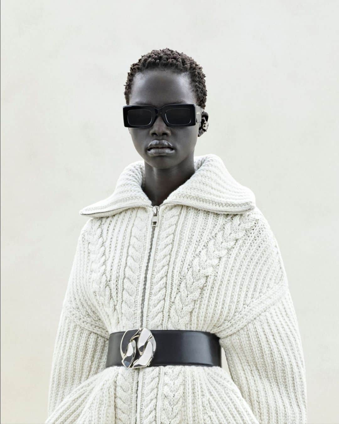 アレキサンダー・マックイーンのインスタグラム：「An ivory cable knit jumper with zip detailing and a slashed biker pencil skirt. Paired with Bold sunglasses, a chain link waist belt and the Slash Biker boots.⁣ ⁣ Discover the #McQueenAW23 collection via the link in bio.⁣ ⁣ Photographed by @Jet.Swan」