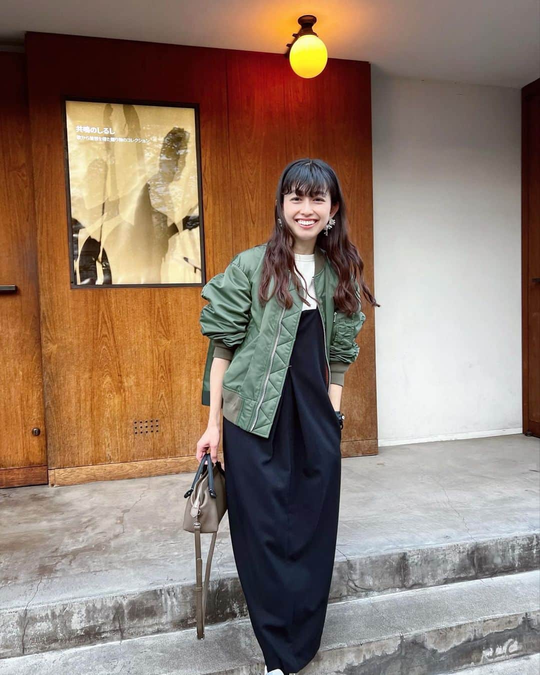 木野園子のインスタグラム：「1日があっという間に過ぎていく💨何だかずっと暖かかったし、毎日バタバタしているから気がつかなかったけど、冬はもうすぐそこに⛄️そして、クリスマス🎄に年末に🎍🧧  撮ってもらった自分の写真を見て、前髪の長さに気がついたり。今日は寒いのにアウターを忘れました。笑  ちゃんとアウターを持っていた日のコーデ🤍  MA1 @sacaiofficial  sweat @nicolasjenson   jumper dress  @muel_chic  sneaker @newbalance  pierce @kalevala_jp  bag @chatona_official」